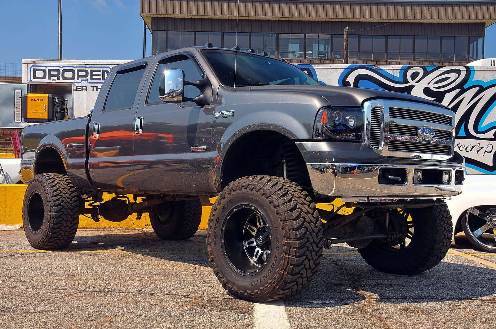 A Gray Truck Parked In A Parking Lot Background