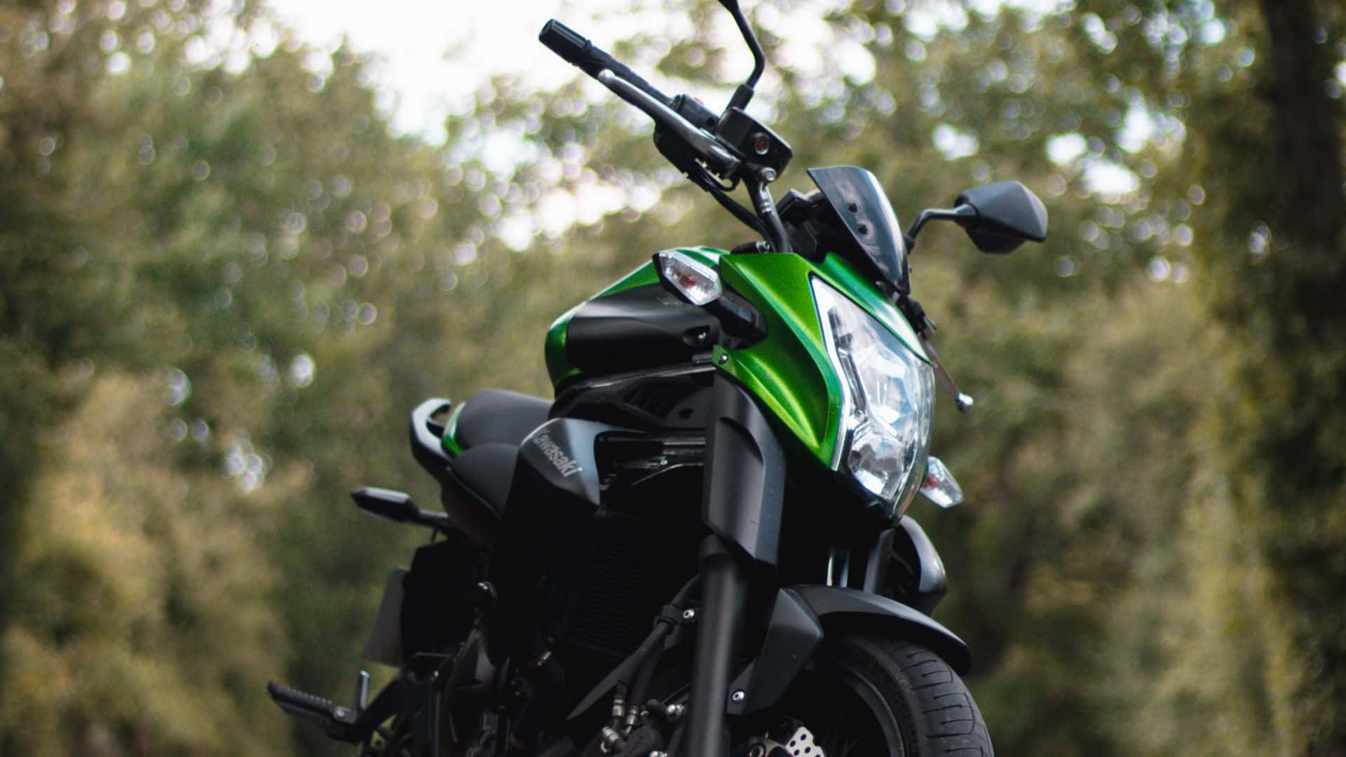 A Green And Black Motorcycle Parked On A Road Background