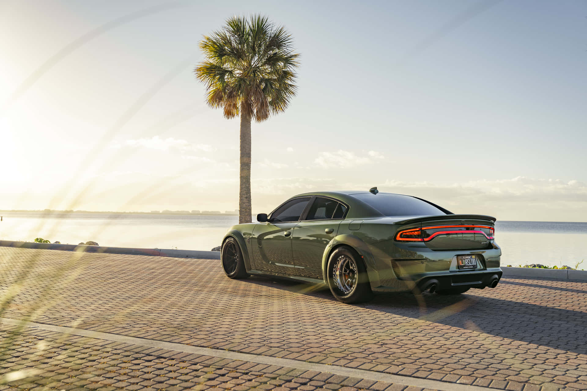 A Green Car Is Parked On A Brick Road Background