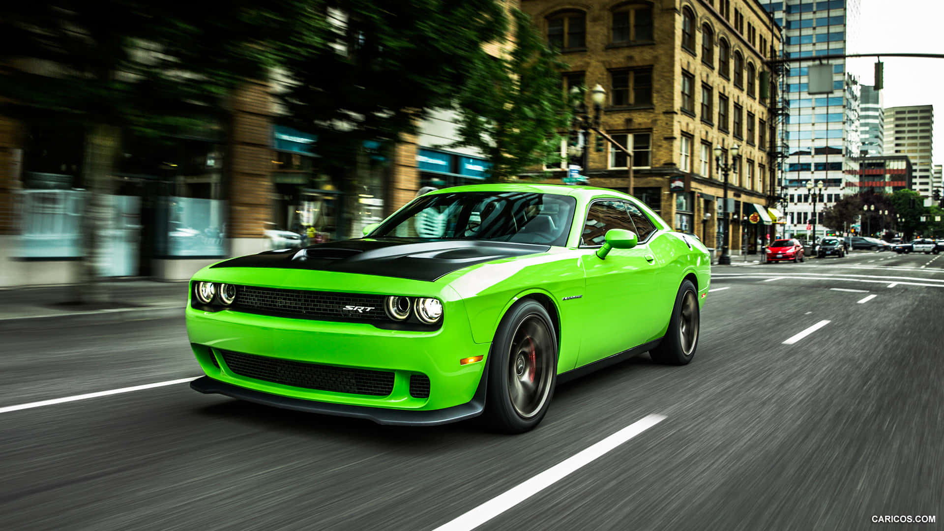 A Green Dodge Challenger Driving Down A City Street