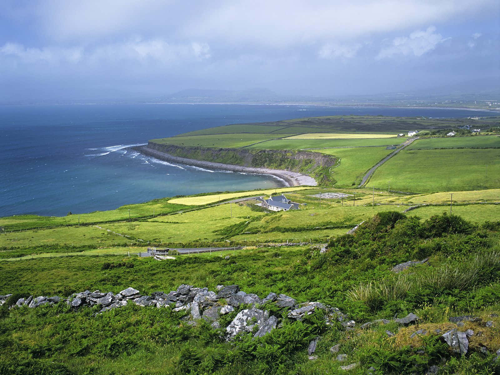 A Green Hillside With A View Of The Ocean Background