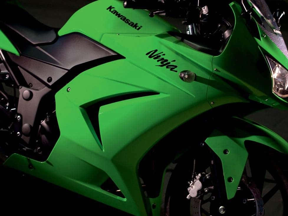 A Green Motorcycle Is Parked In A Dark Room Background