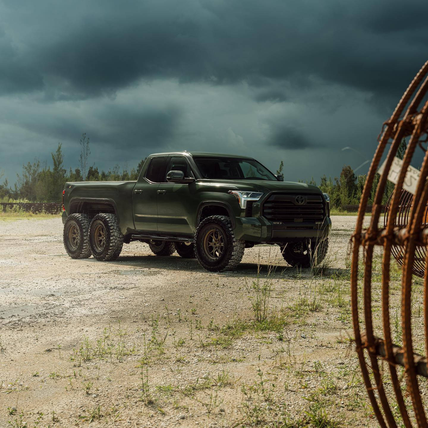 A Green Truck Is Parked In A Field With A Wire Fence Background