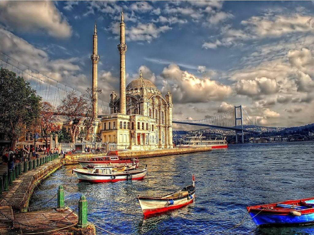 A Group Of Boats Are Docked Near A Mosque Background