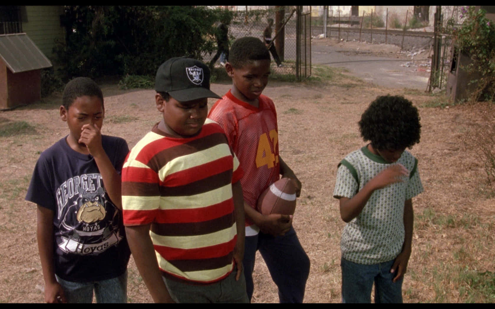 A Group Of Boys Standing In A Field With A Football Background