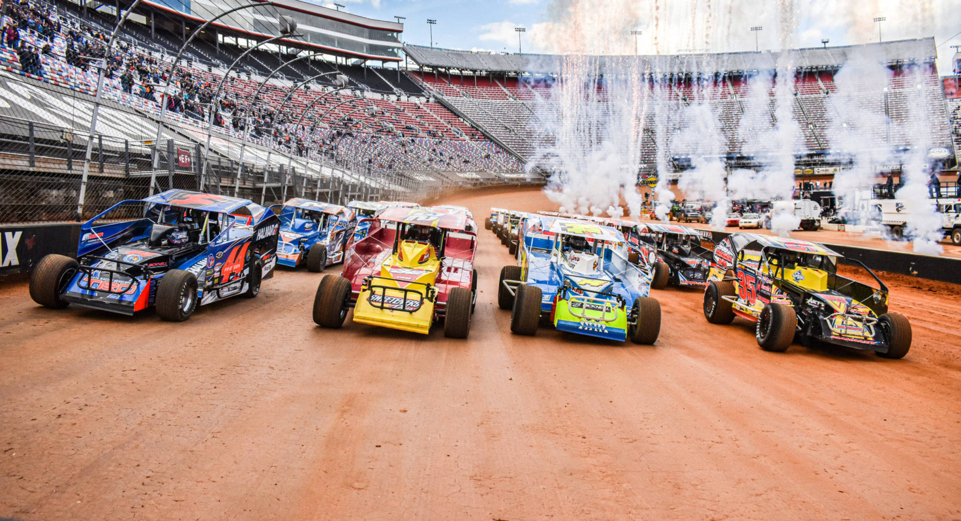 A Group Of Dirt Track Cars Driving In A Stadium Background