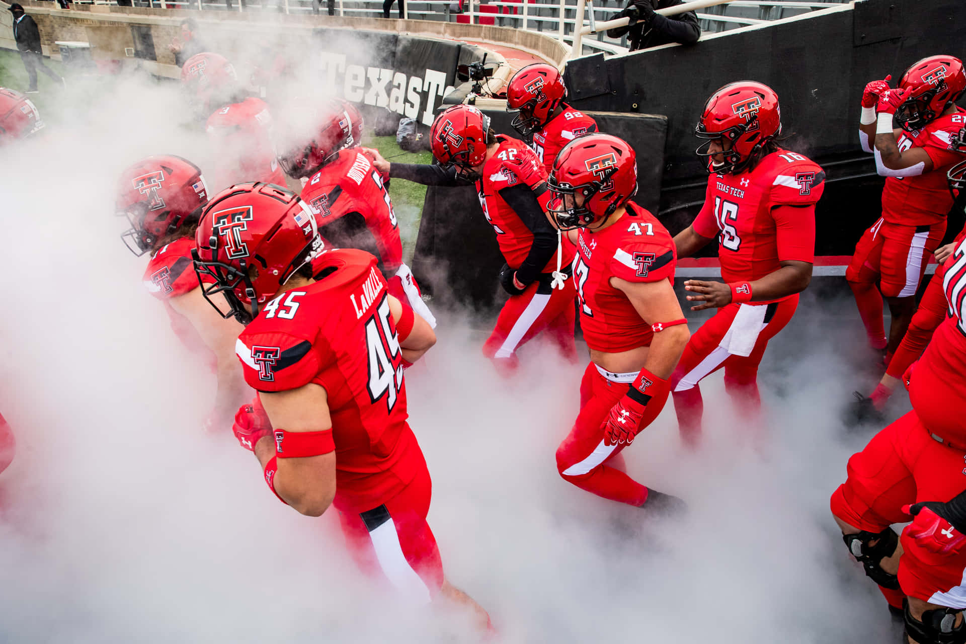 A Group Of Football Players Walking Through Smoke Background