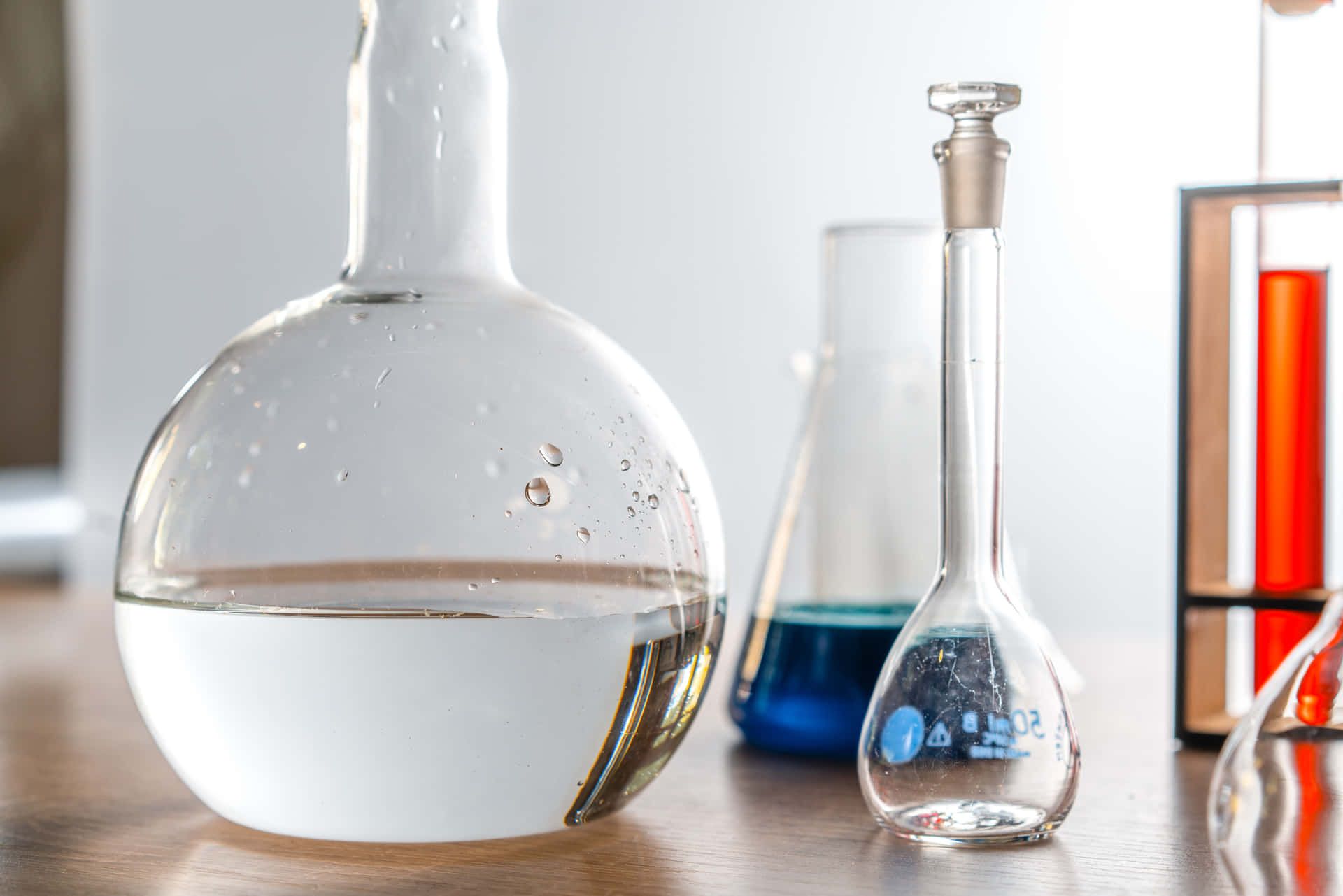 A Group Of Laboratory Flasks And A Glass Of Water Background