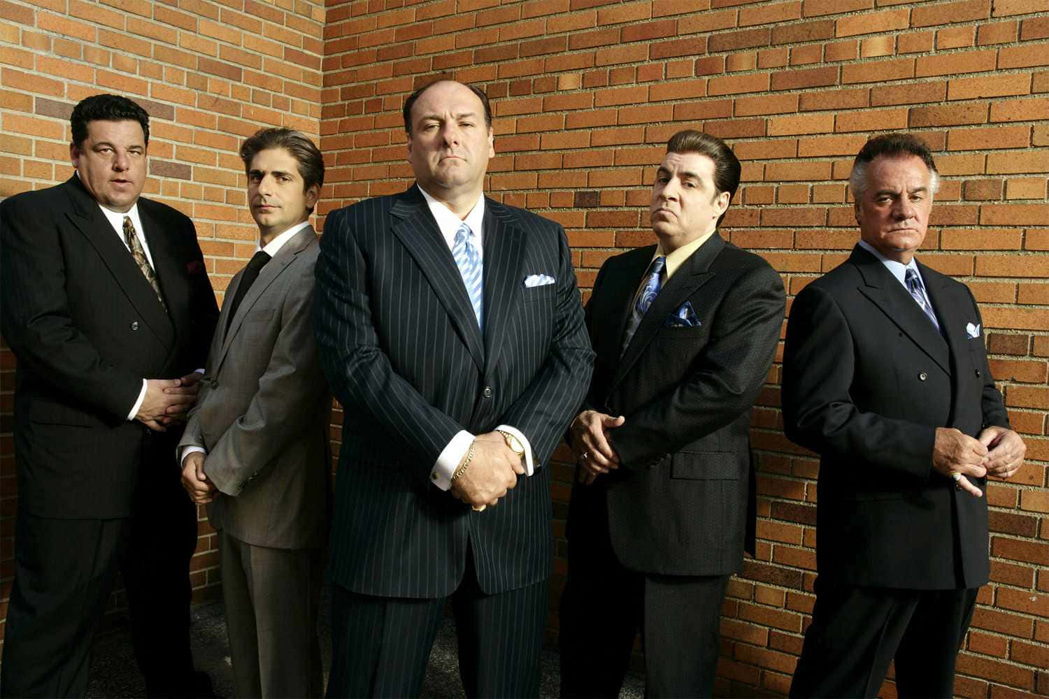 A Group Of Men In Suits Standing Next To A Brick Wall Background