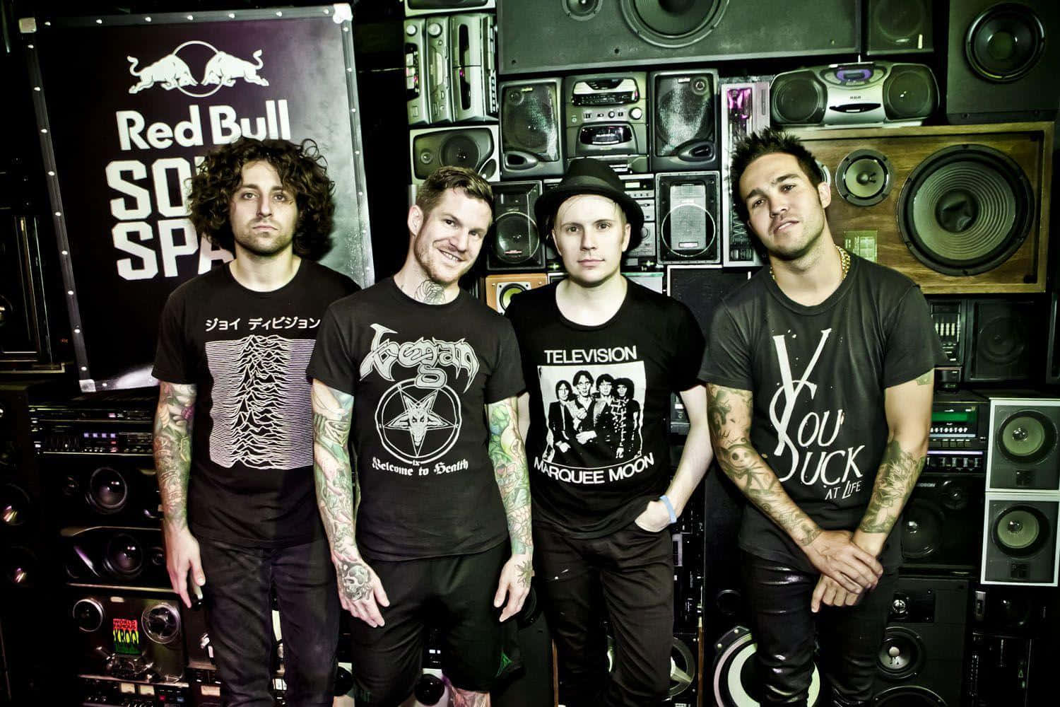 A Group Of Men Standing In Front Of A Speaker Background