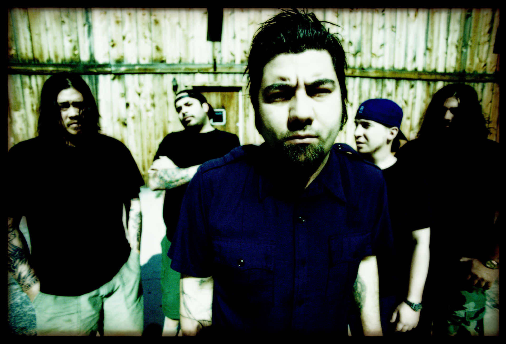 A Group Of Men Standing In Front Of A Wooden Building Background