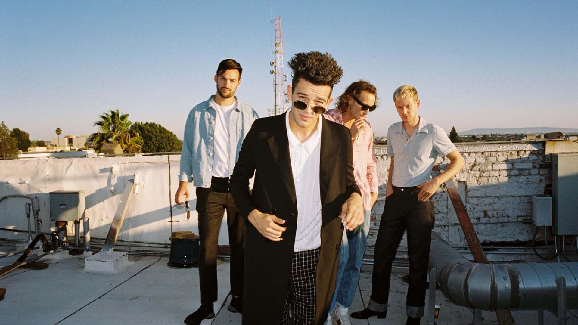 A Group Of Men Standing On A Roof Background