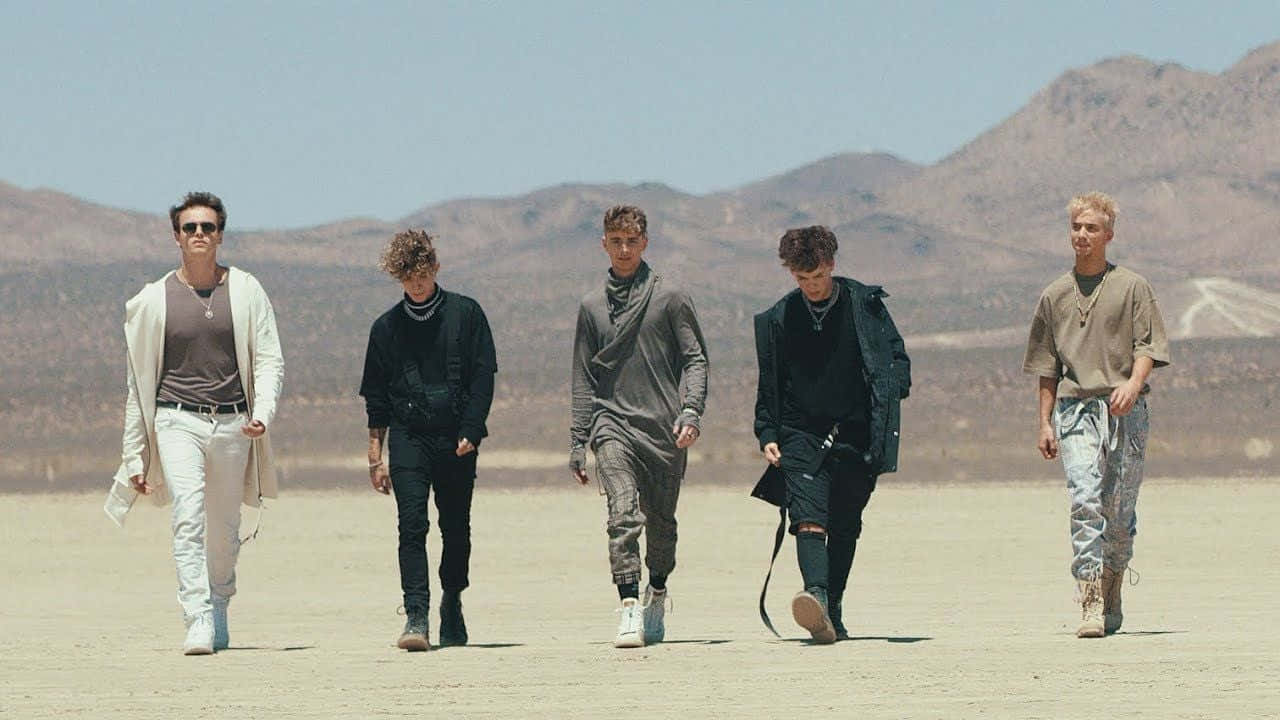 A Group Of Men Walking In The Desert Background