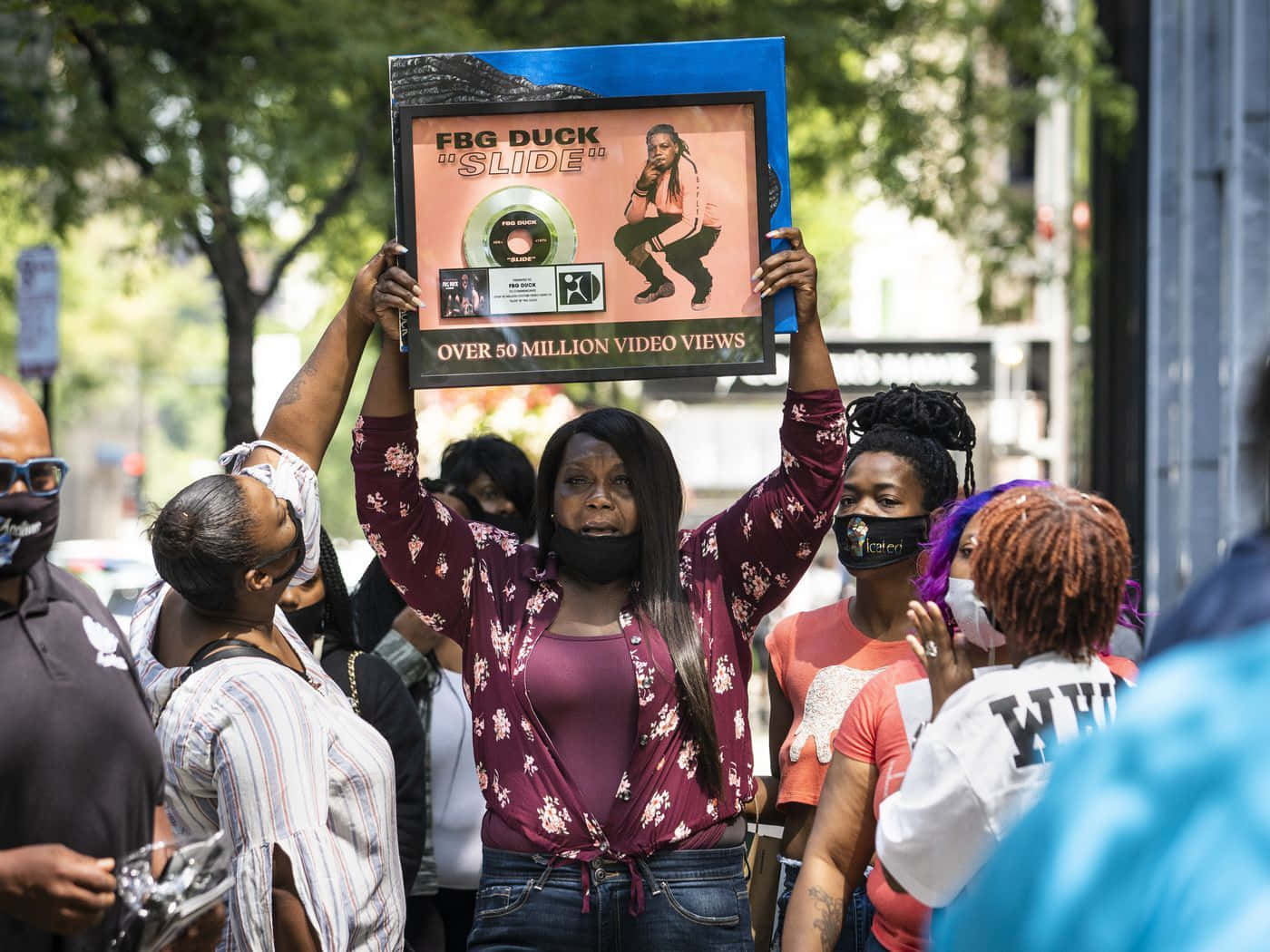 A Group Of People Holding Up A Sign In Front Of A Crowd Background