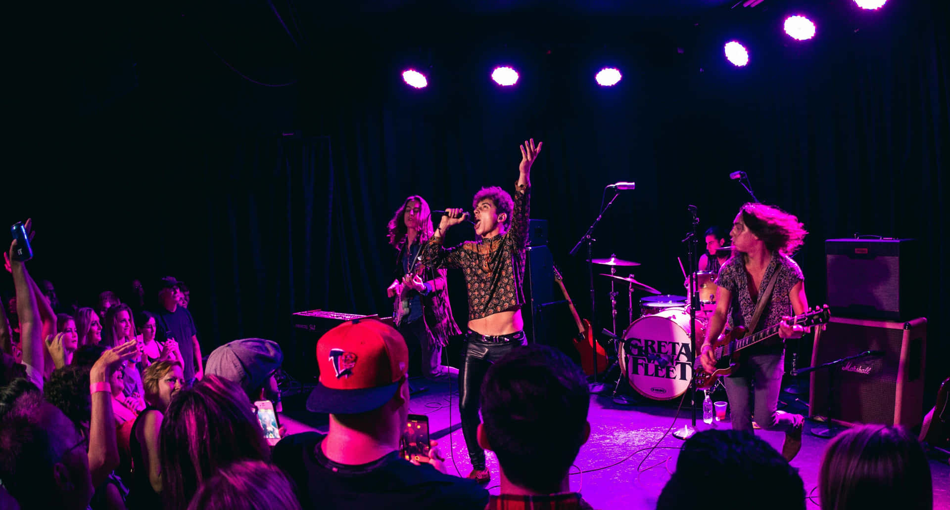 A Group Of People On Stage With A Microphone Background