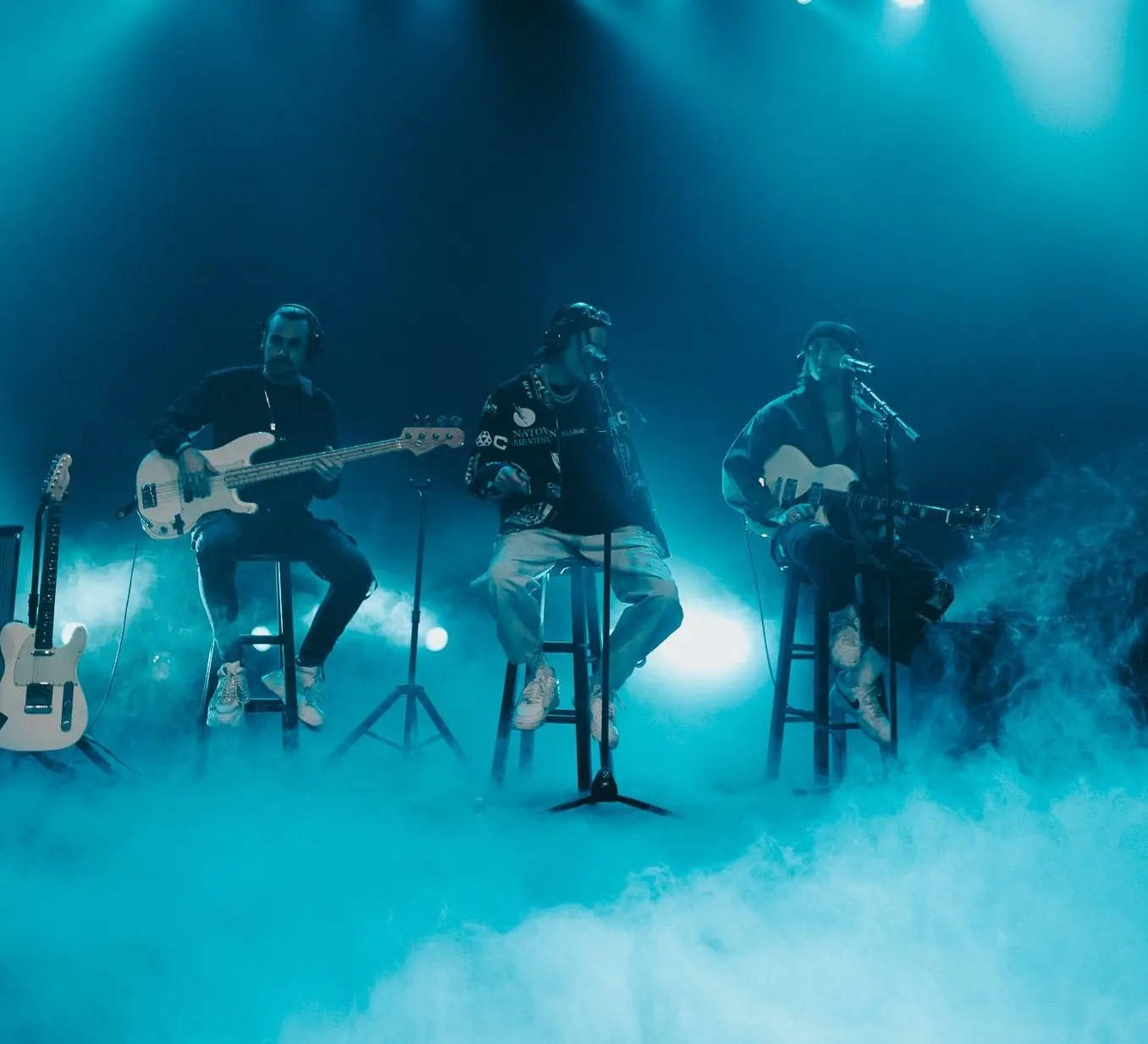 A Group Of People On Stage With Guitars And Smoke Background