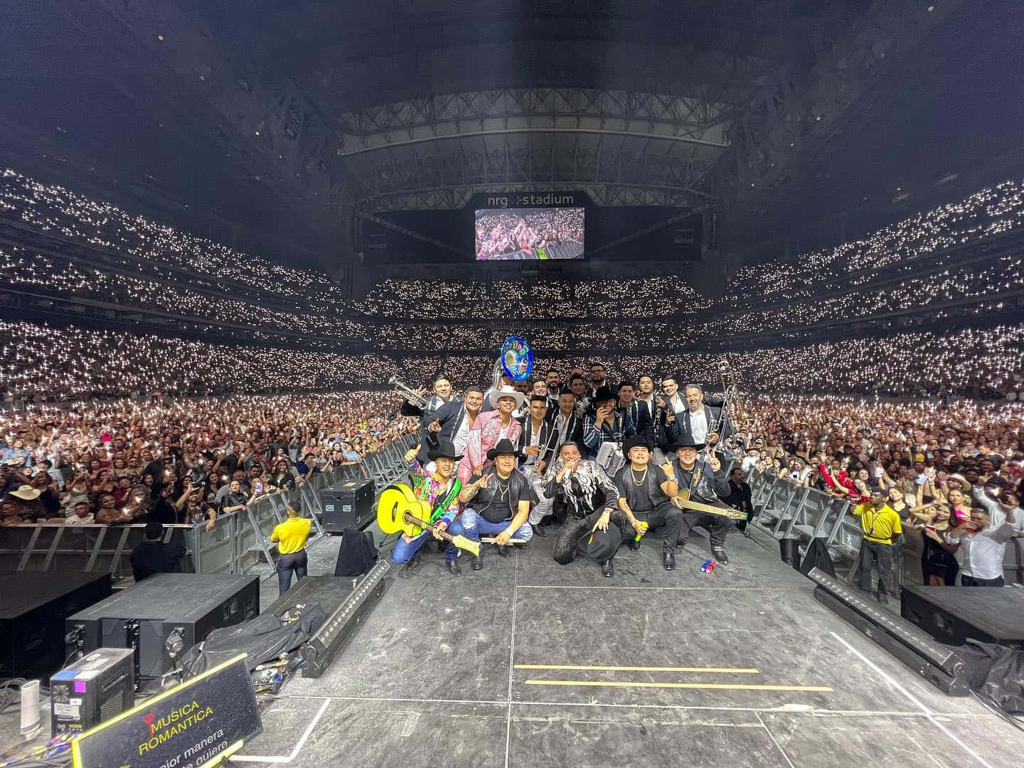 A Group Of People Posing On Stage In A Large Stadium Background