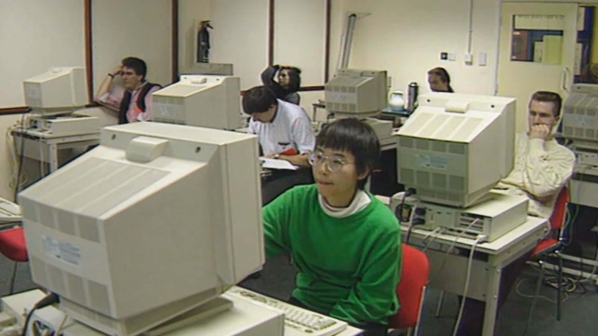 A Group Of People Sitting In Front Of Computers Background