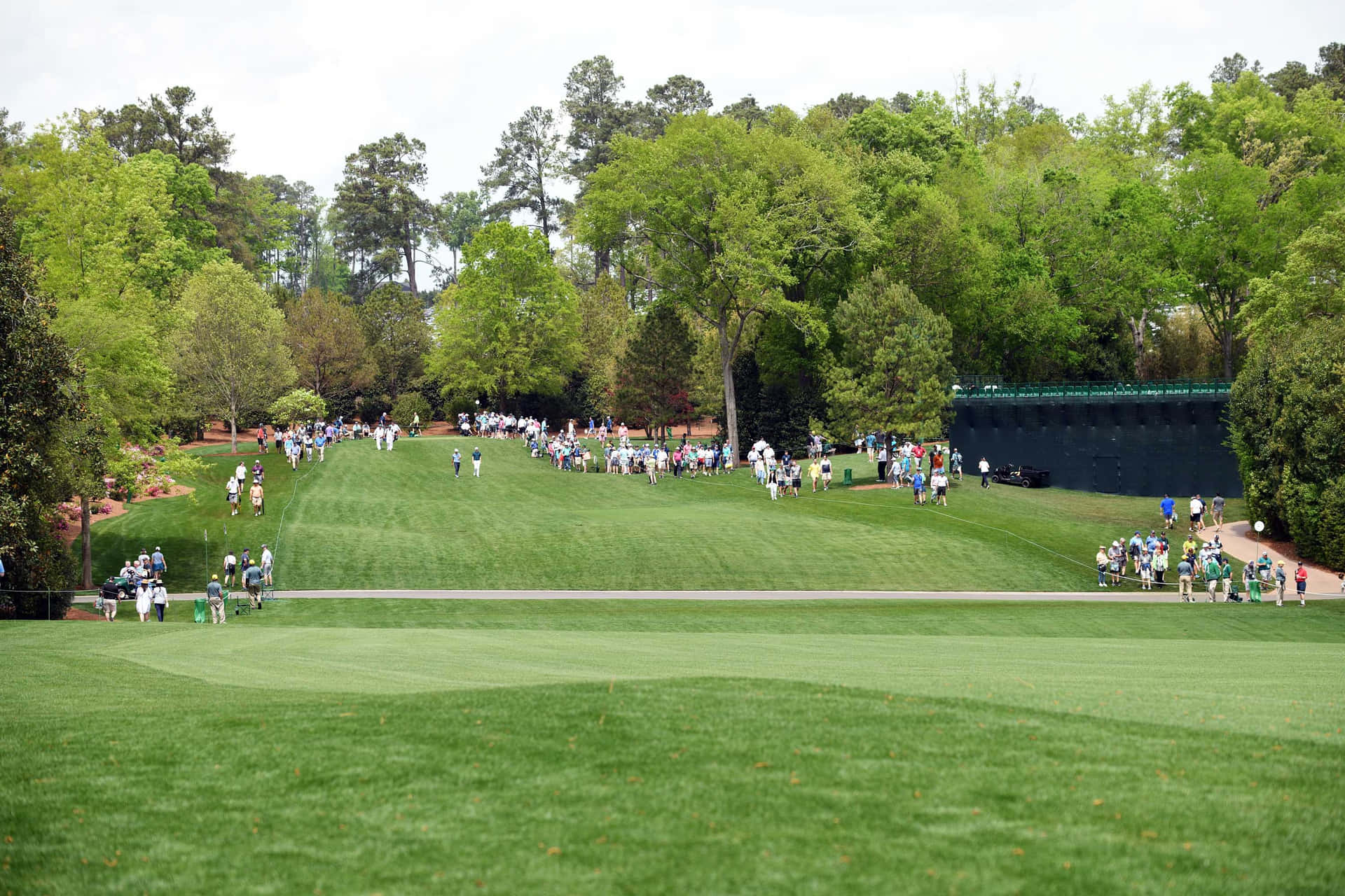 A Group Of People Walking Down A Green Golf Course Background