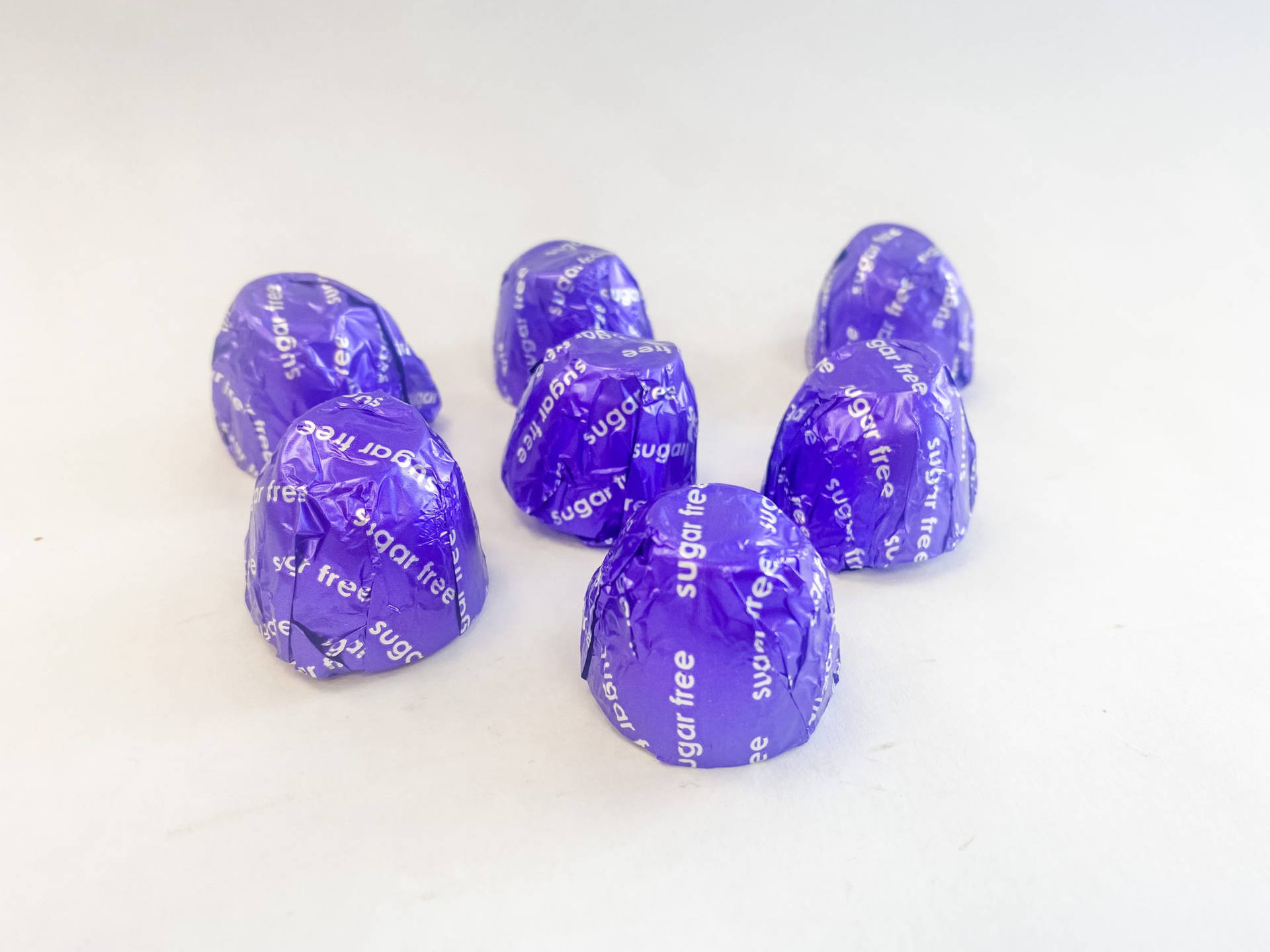 A Group Of Purple Chocolates On A White Surface Background