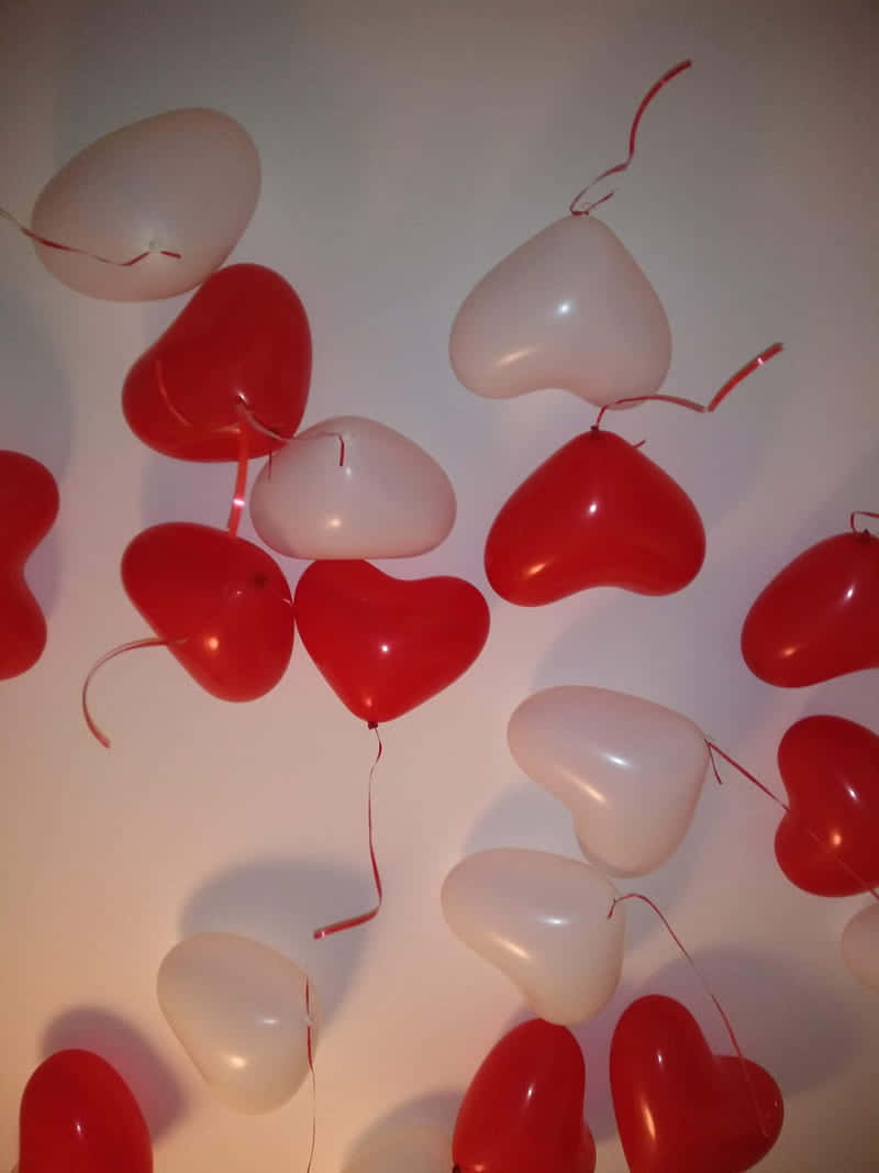 A Group Of Red And White Balloons Hanging From A Ceiling Background