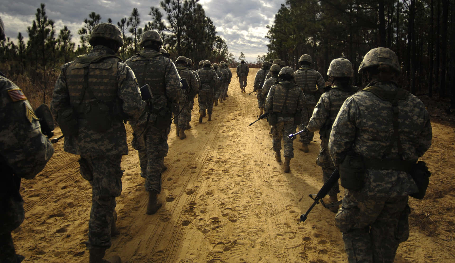 A Group Of Soldiers Walking Down A Dirt Road Background