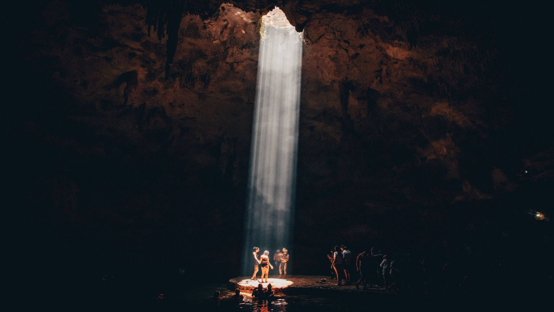 A Group Of Tourists Exploring An Impressive Natural Cave Background