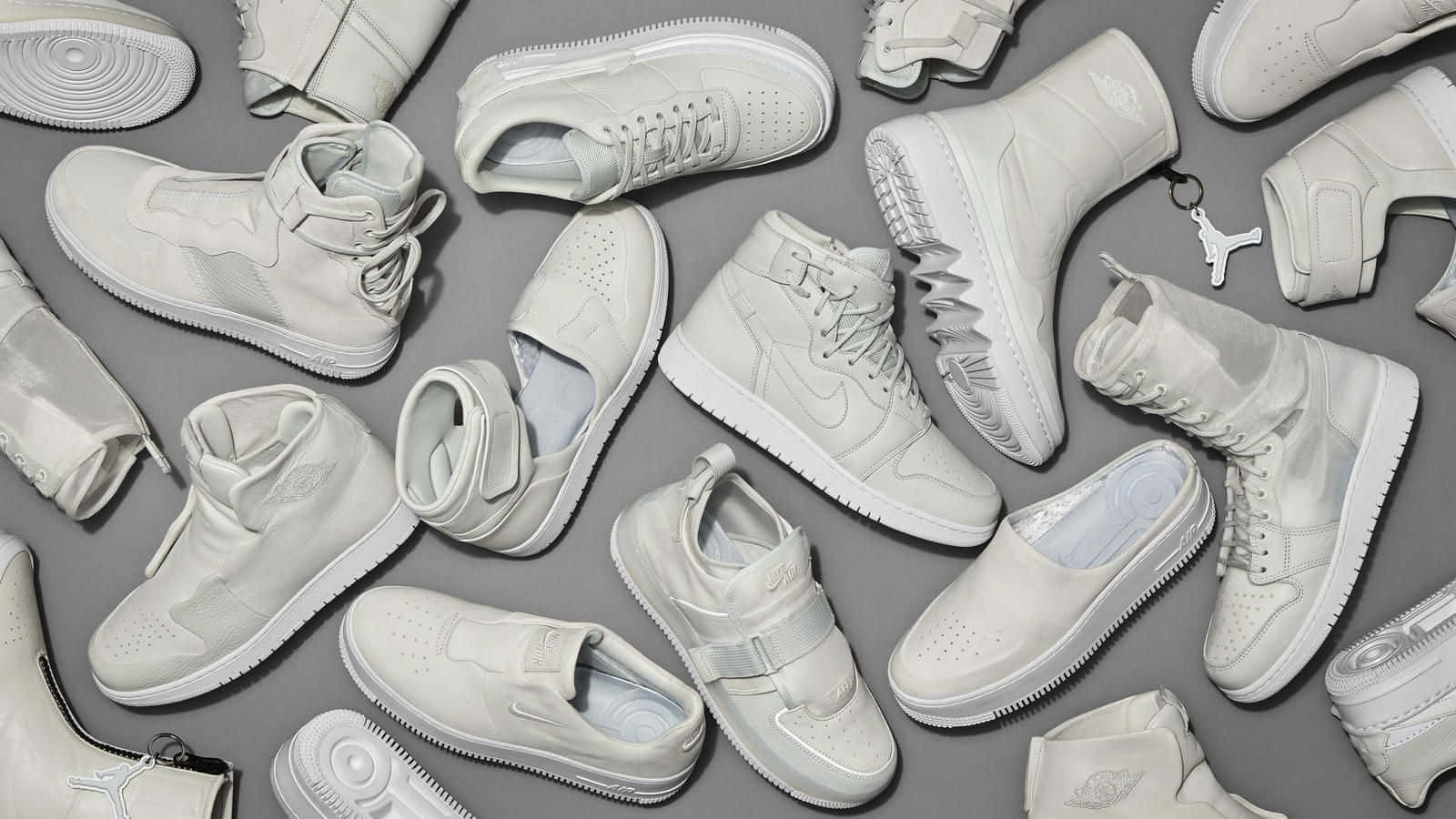 A Group Of White Sneakers Arranged On A Grey Background Background