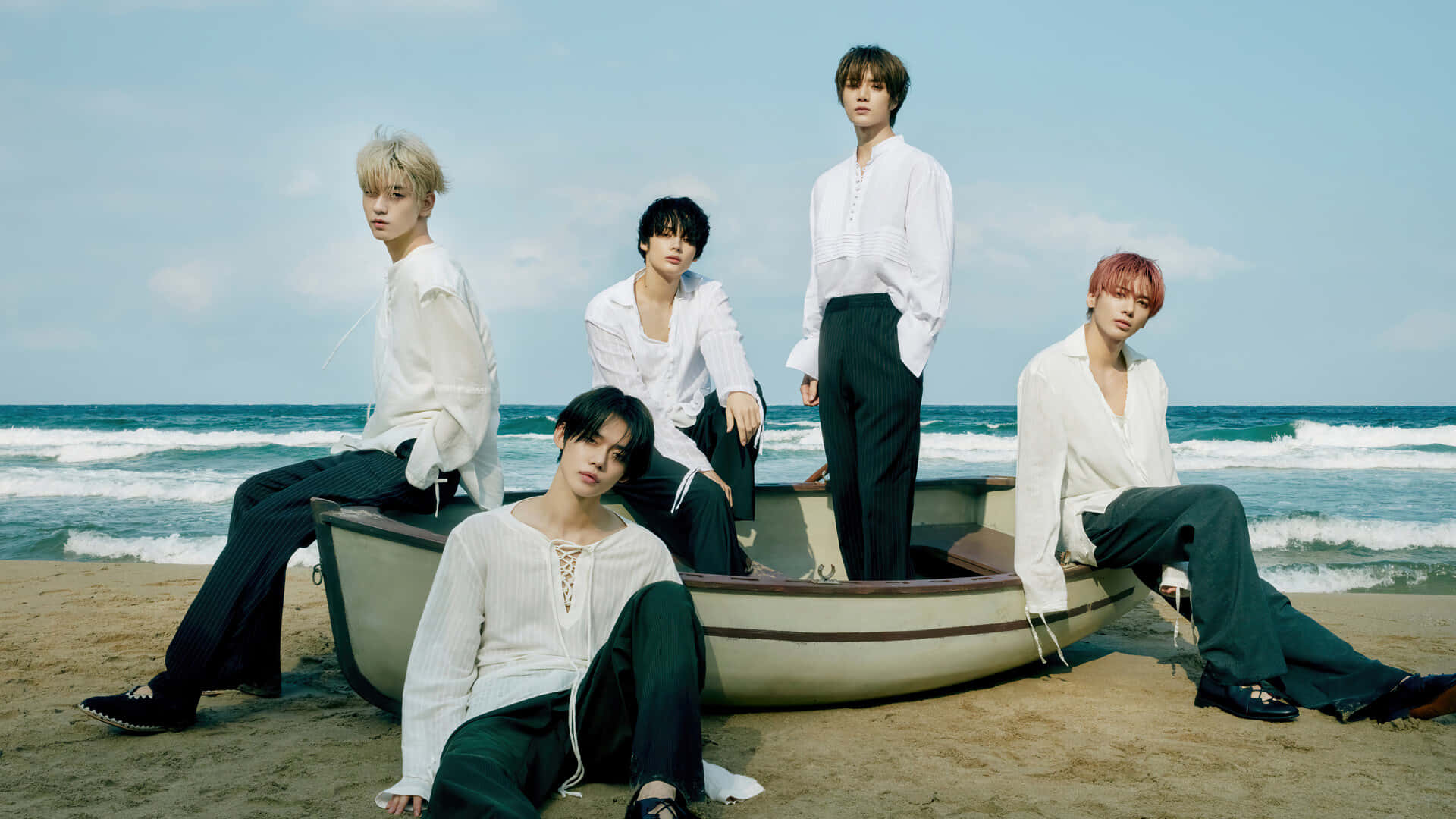 A Group Of Young Men Sitting On A Boat On The Beach Background