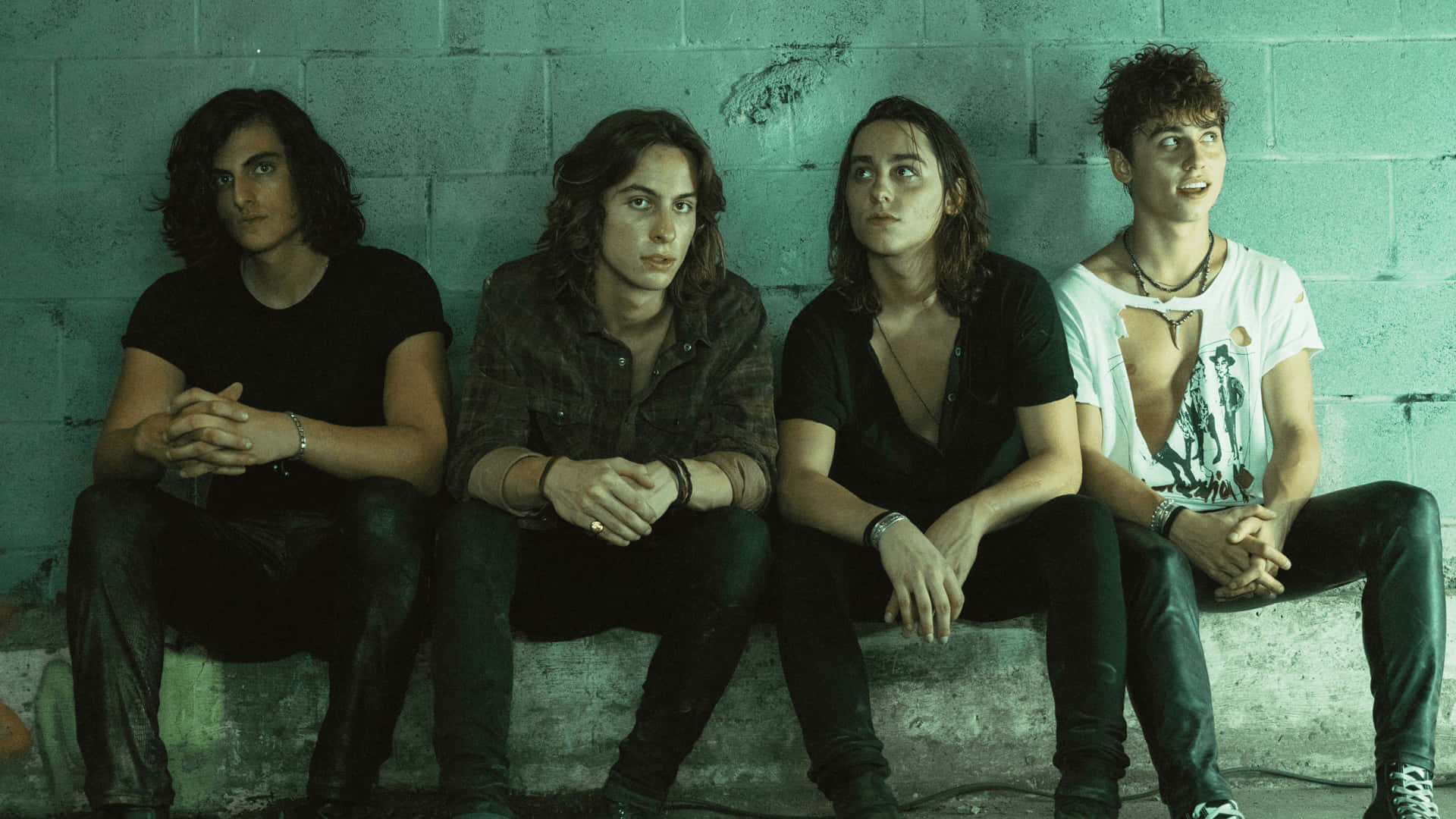 A Group Of Young Men Sitting On A Wall Background