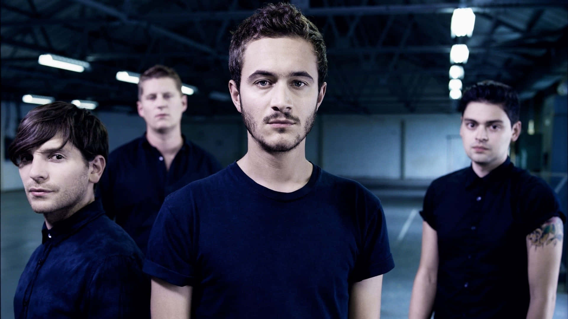 A Group Of Young Men Standing In A Dark Room