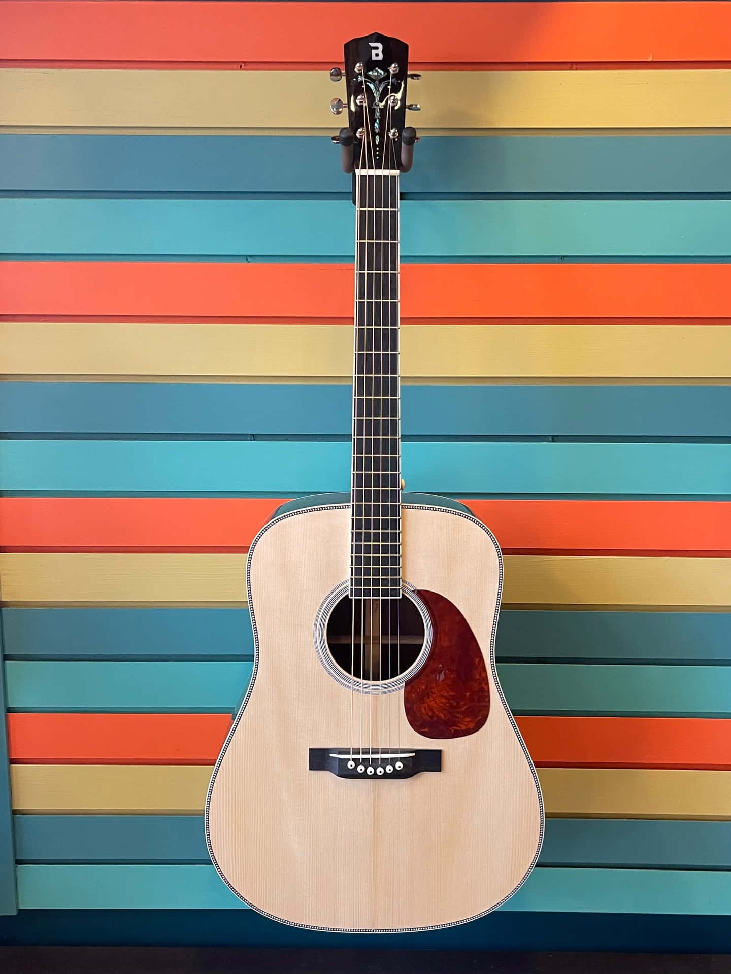 A Guitar Is Sitting Against A Colorful Wall