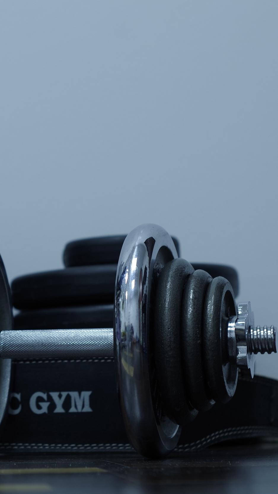 A Gym Dumbbell And A Black Belt On A Table Background