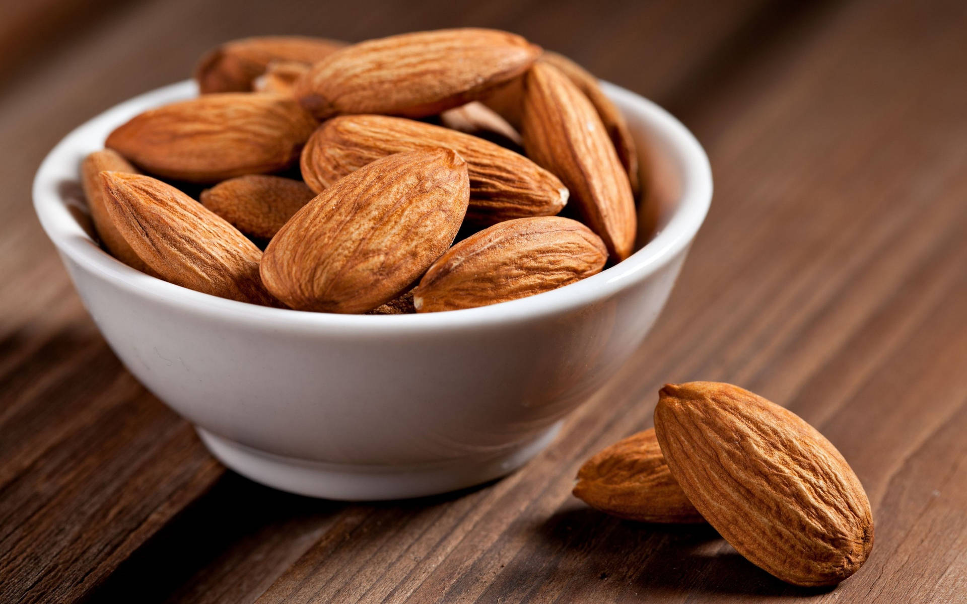 A Handful Of Almonds In A White Ceramic Bowl Background