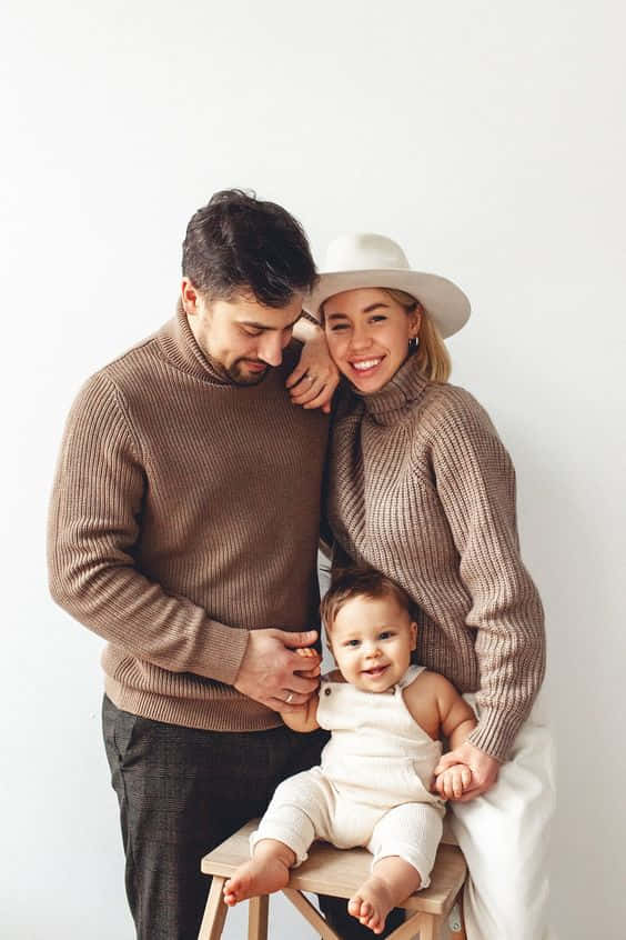 A Happy Family Of Four Cuddling In A Park.