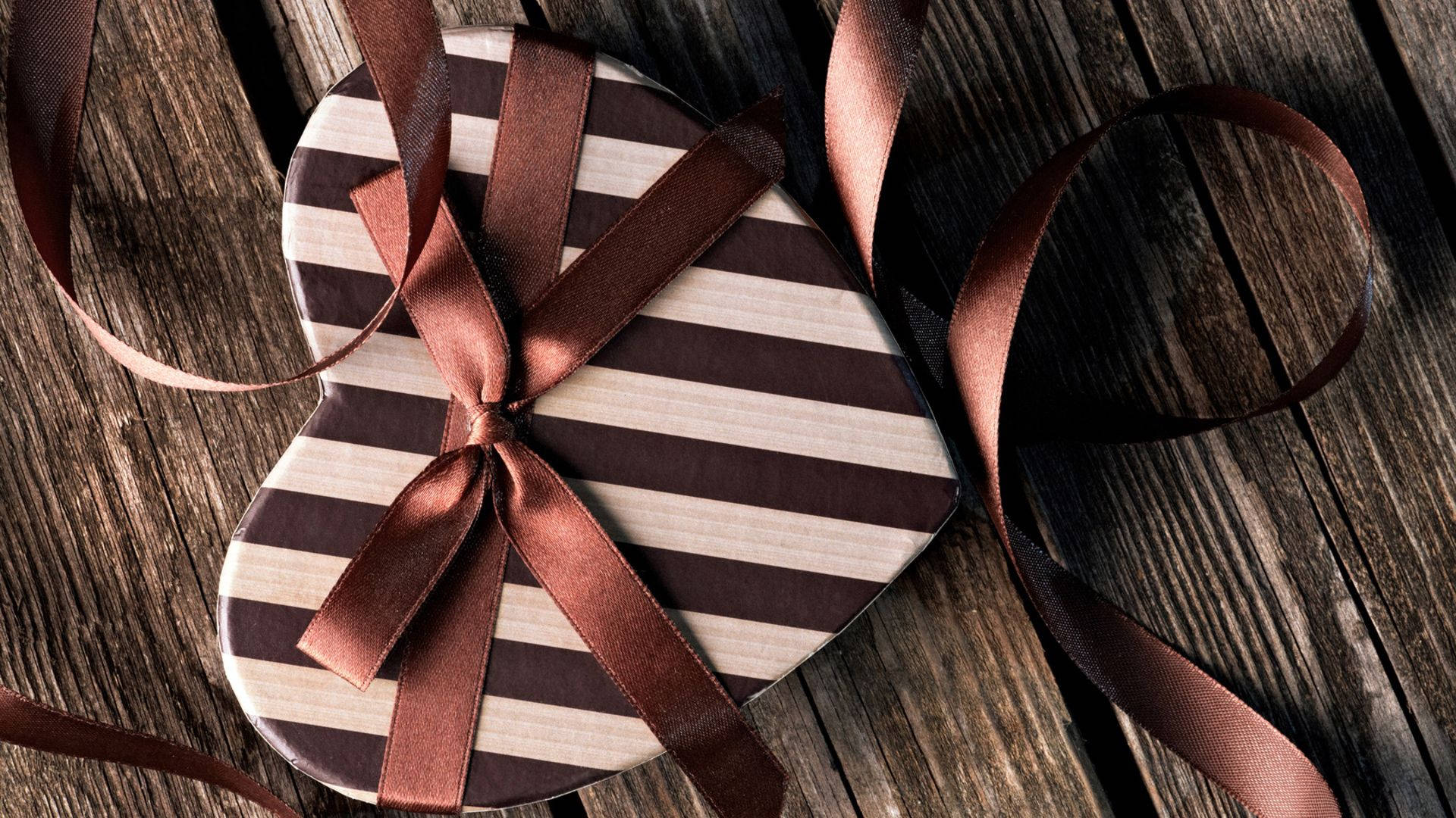 A Heart Shaped Box With A Brown Ribbon Background