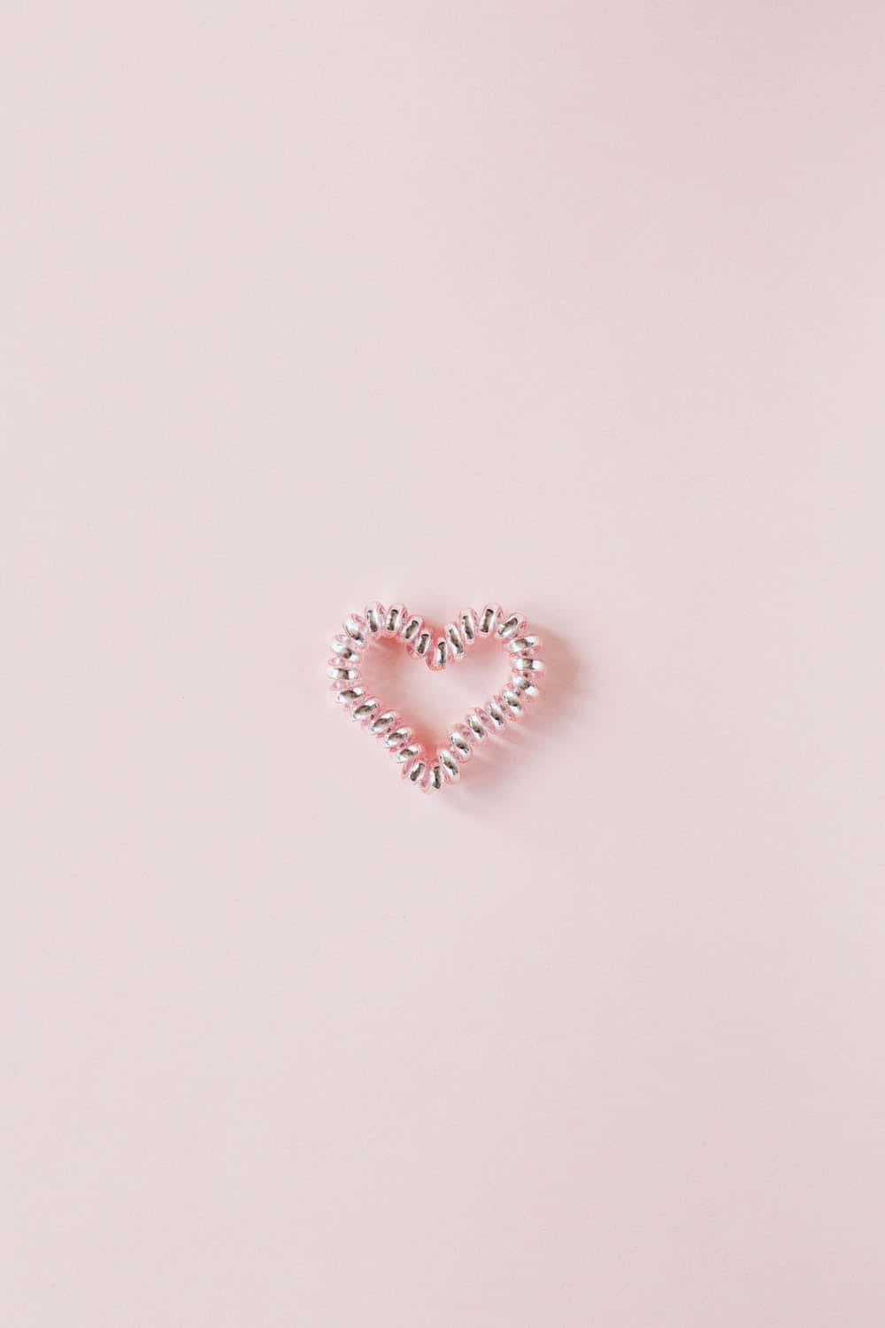 A Heart Shaped Hair Clip On A Pink Background Background