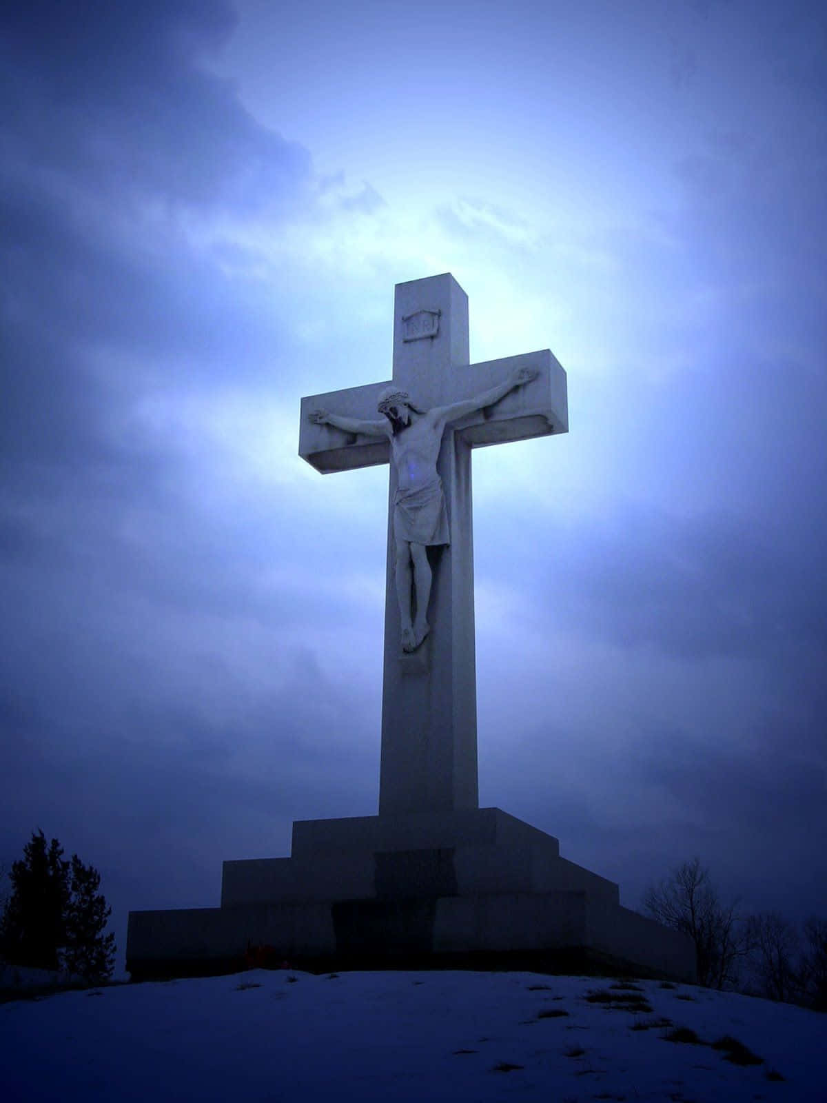 A Jesus Cross Is On Top Of A Hill With A Blue Sky Background