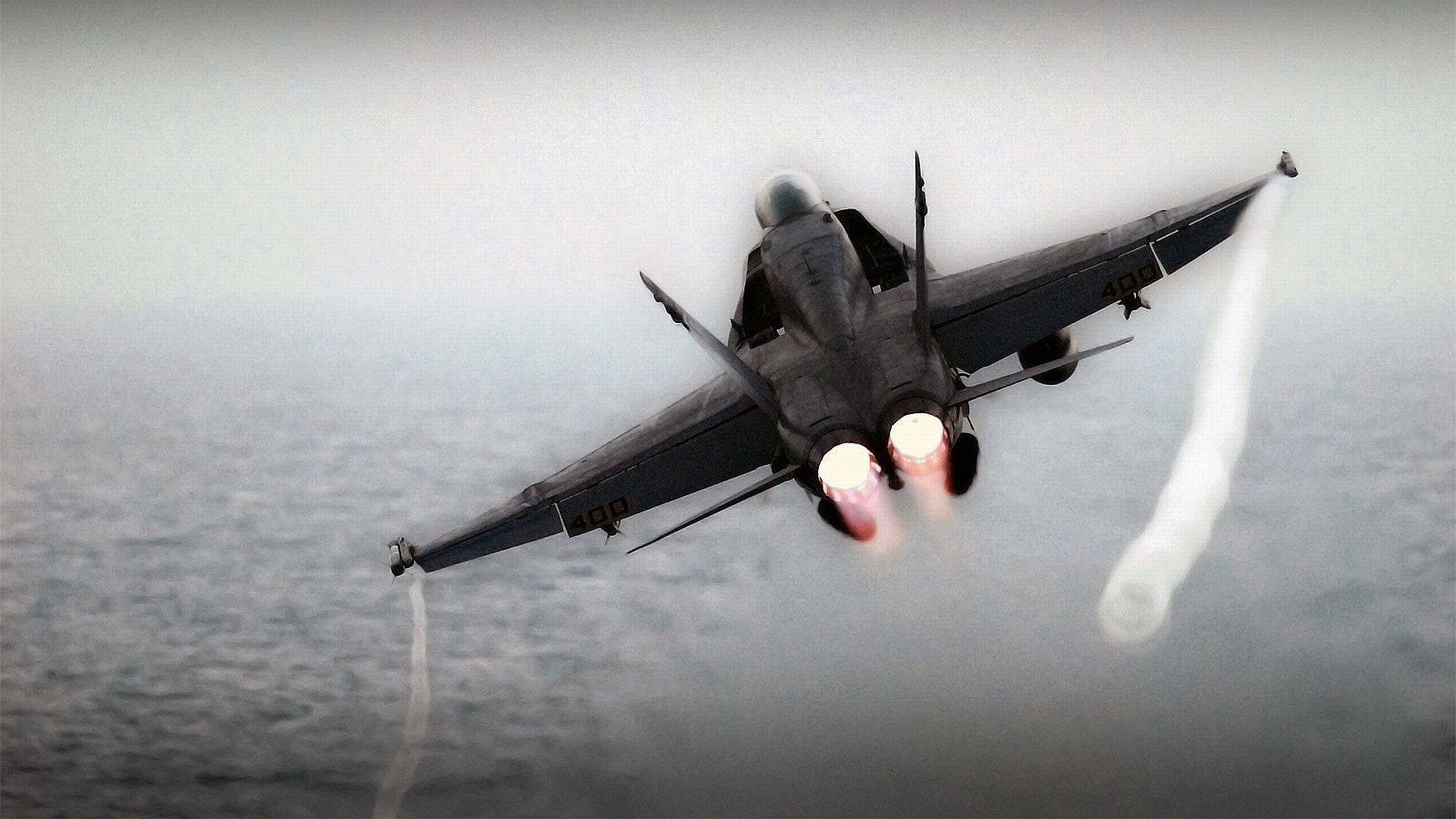 A Jet Fighter Flying Over The Ocean Background