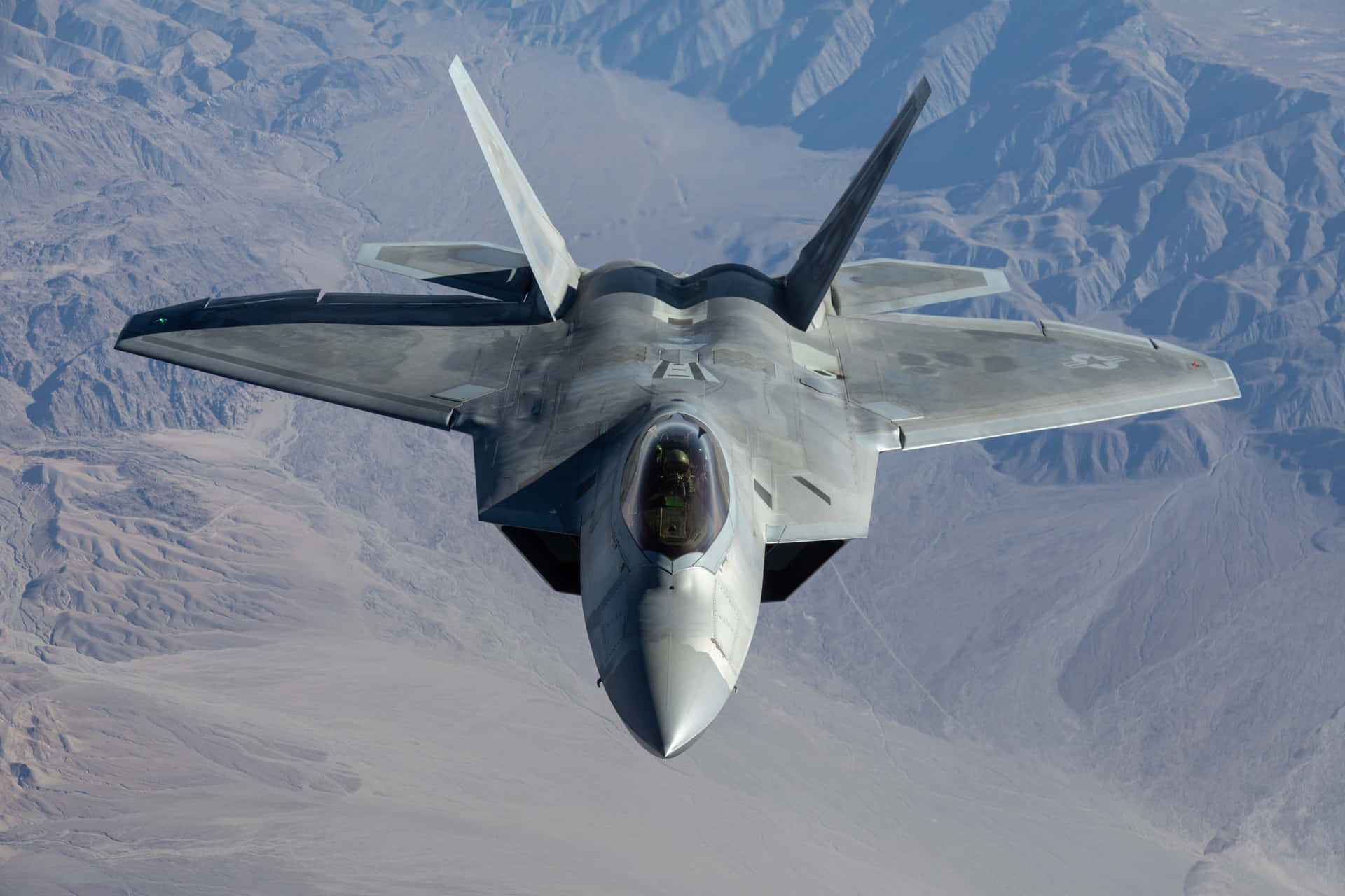 A Jet Flying Over A Mountain Background