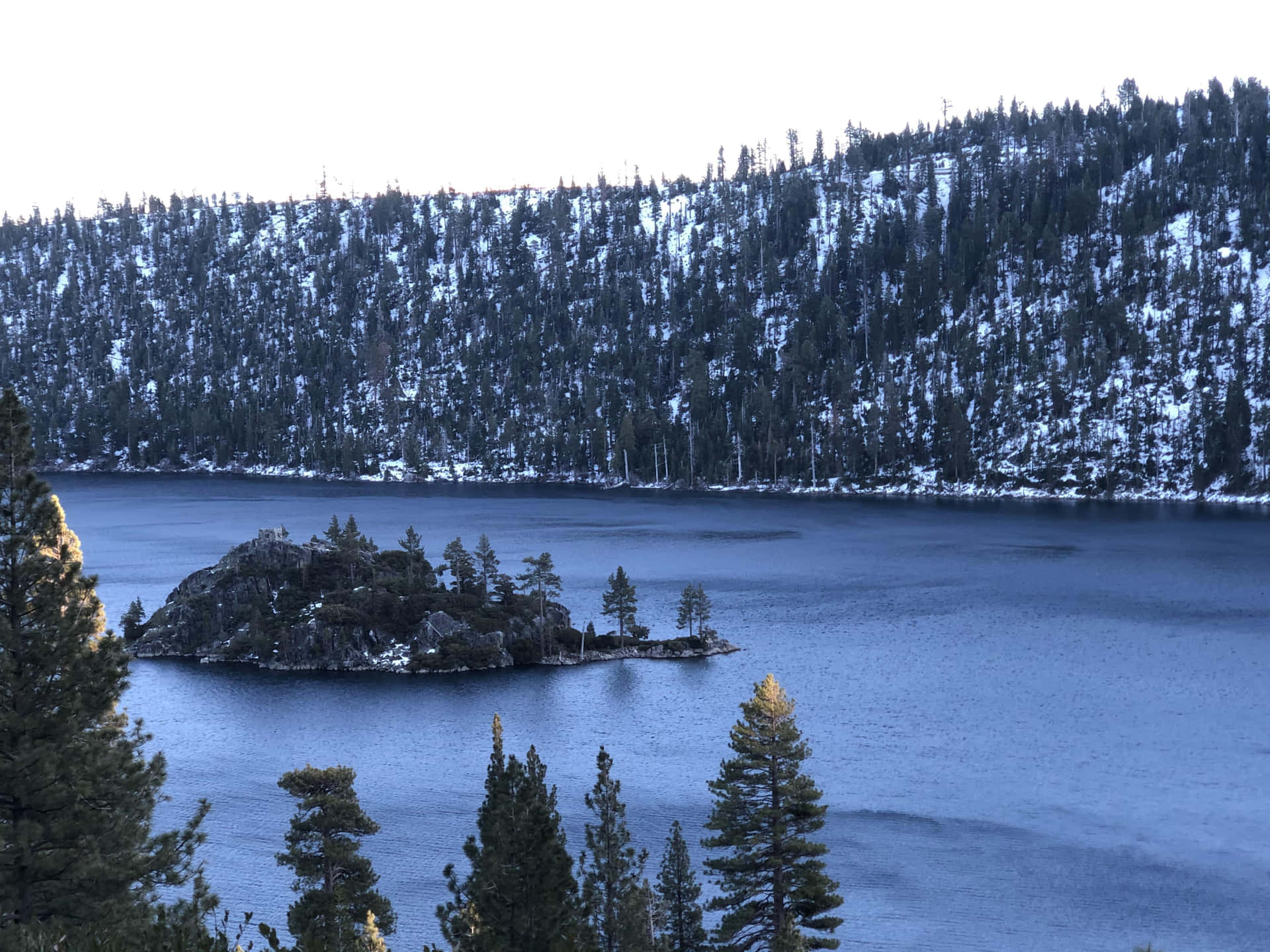 A Lake Surrounded By Trees And Snow Background