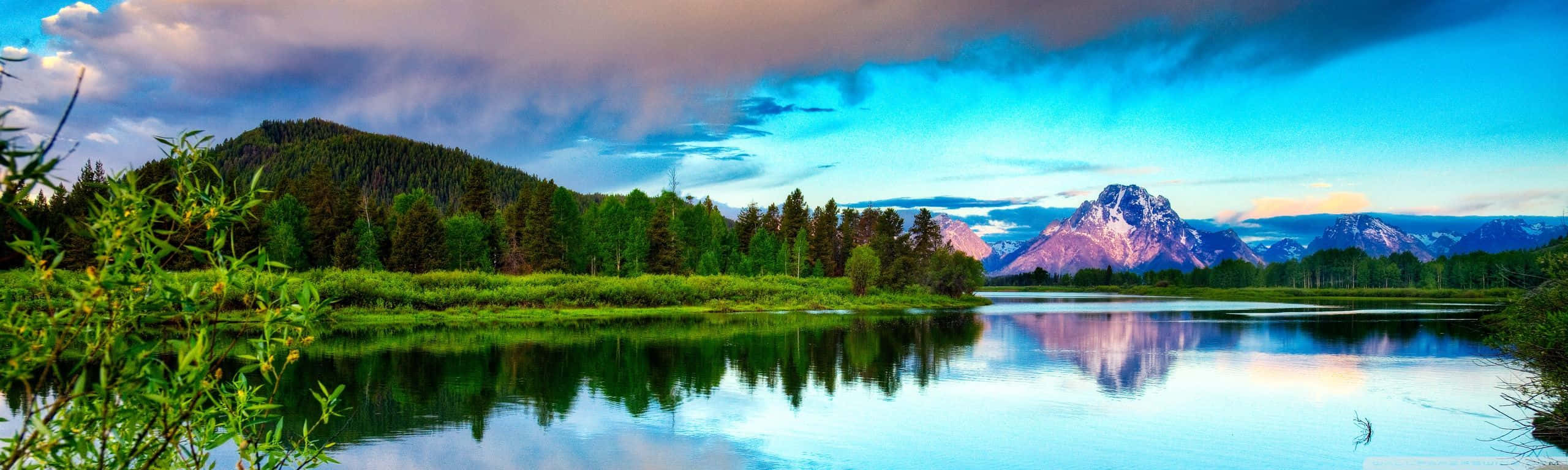 A Lake With Mountains And Clouds In The Background Background