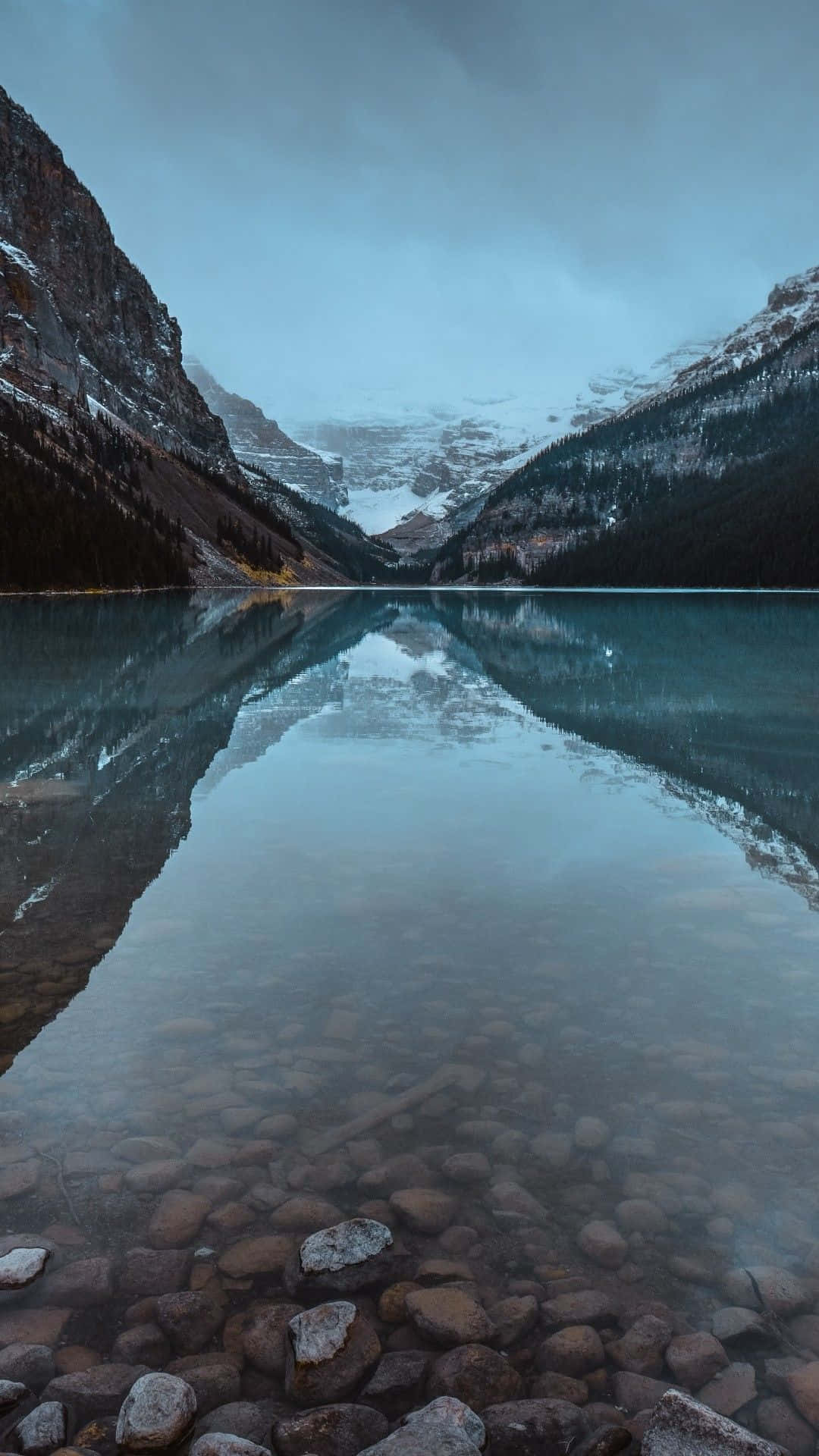 A Lake With Rocks And A Mountain In The Background Background