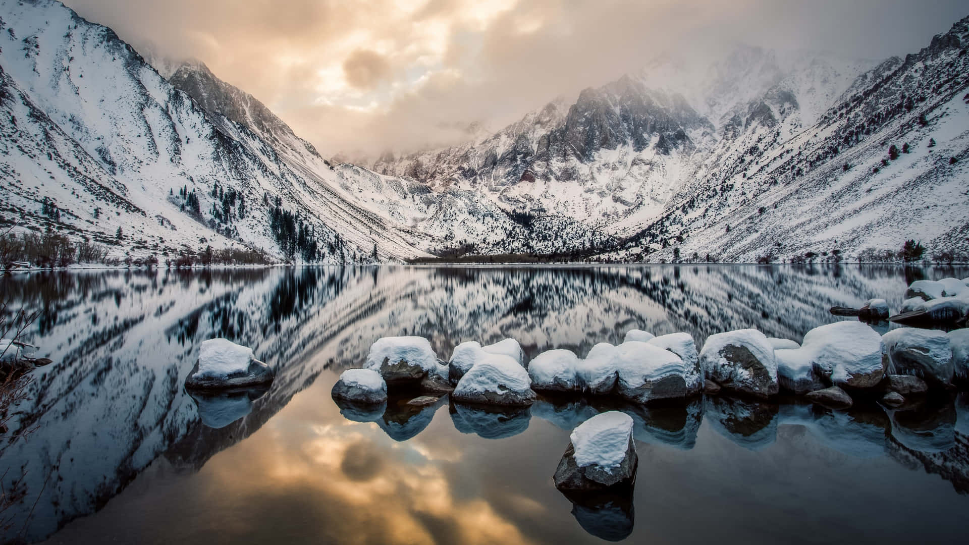 A Lake With Rocks And Snow In The Background Background