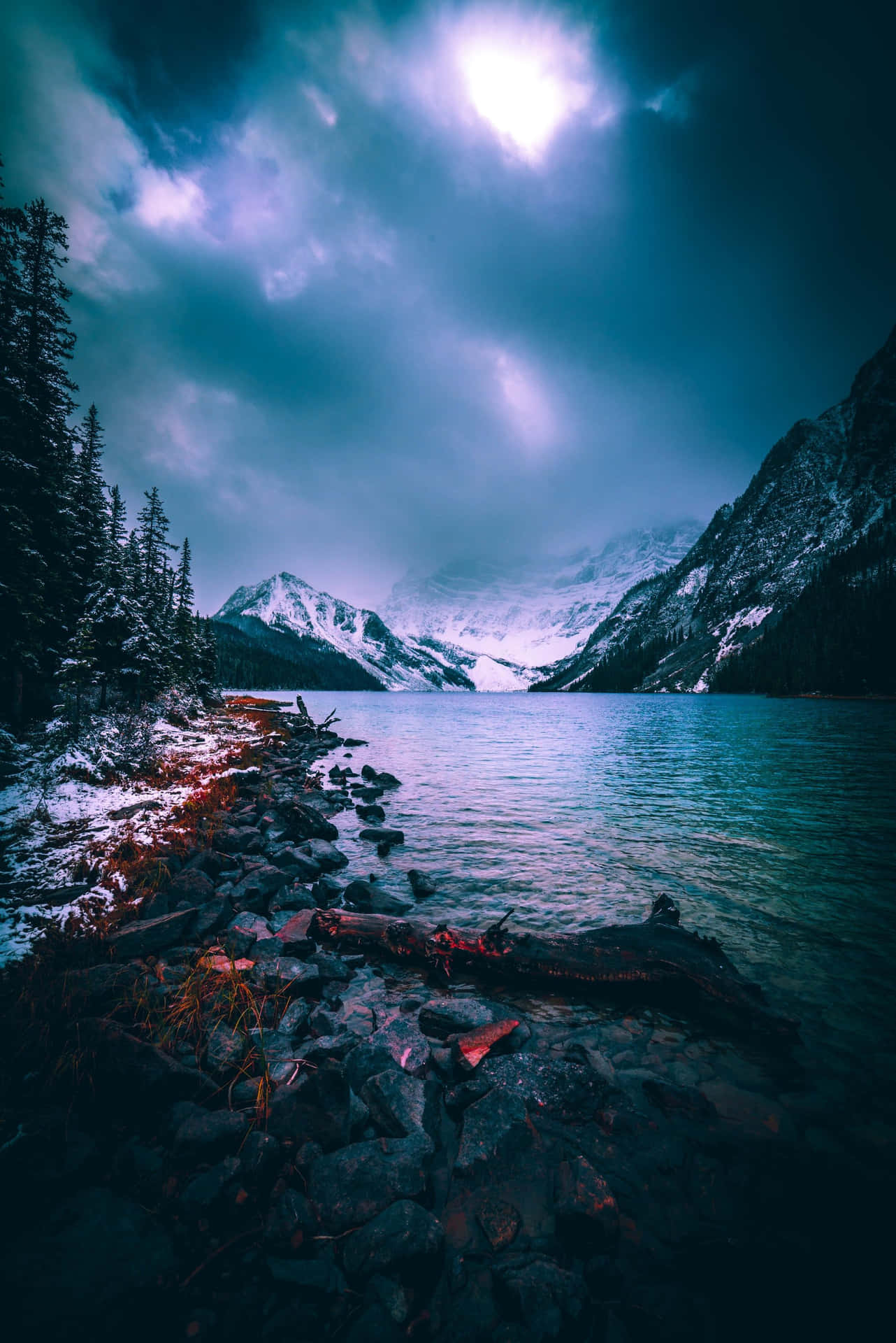 A Lake With Snow Covered Mountains And Trees Background