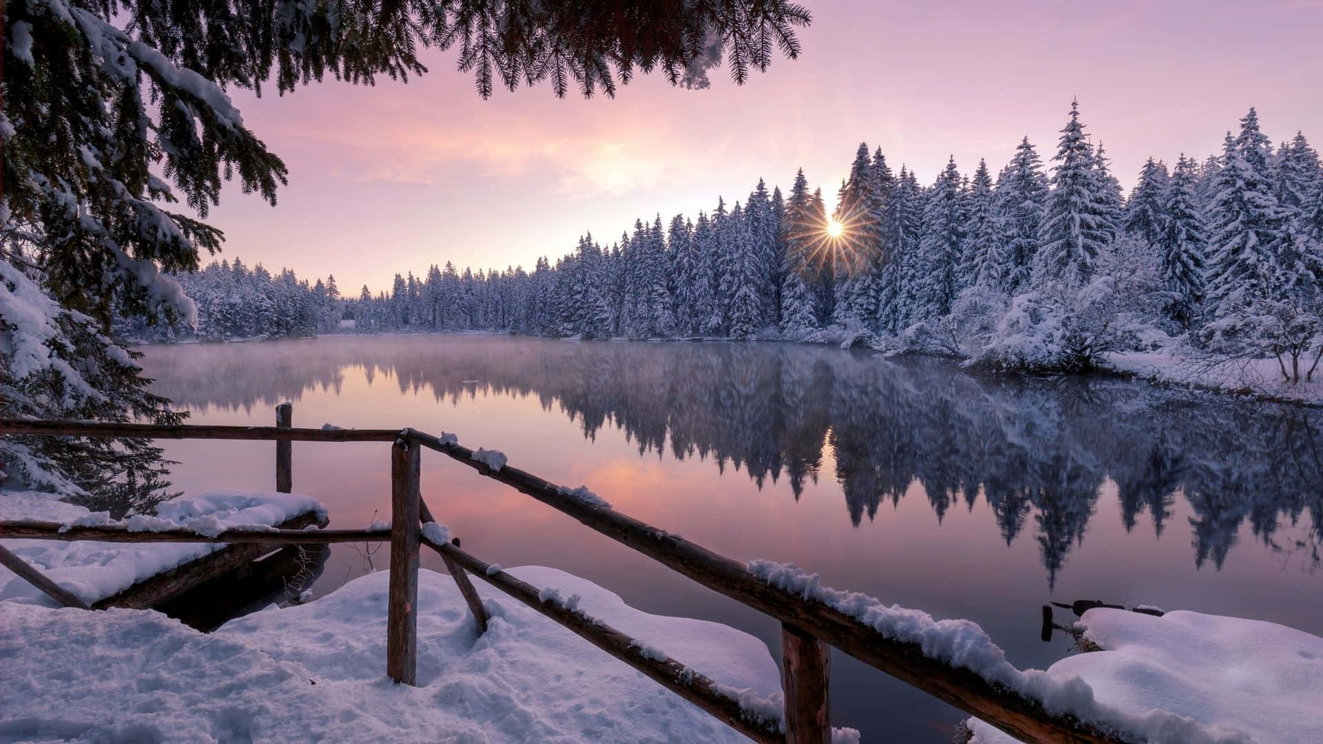 A Lake With Snow Covered Trees And A Bridge Background