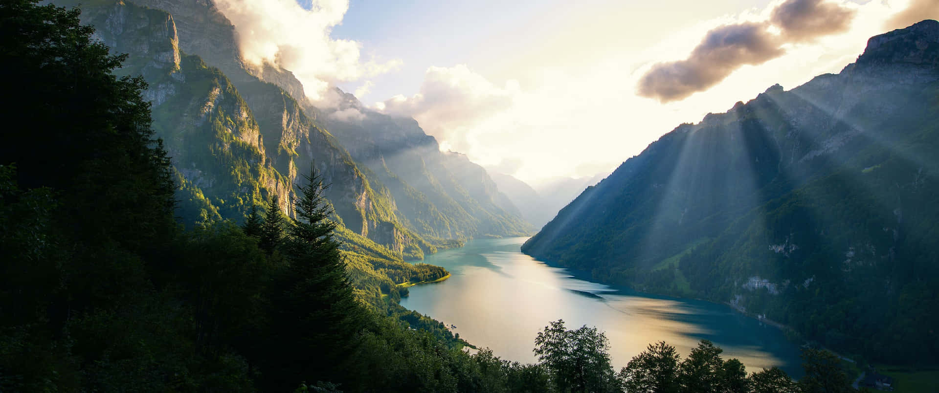 A Lake With Sun Rays Shining Through The Clouds Background