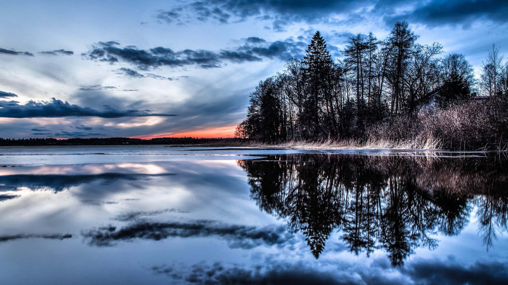 A Lake With Trees And Clouds In The Background