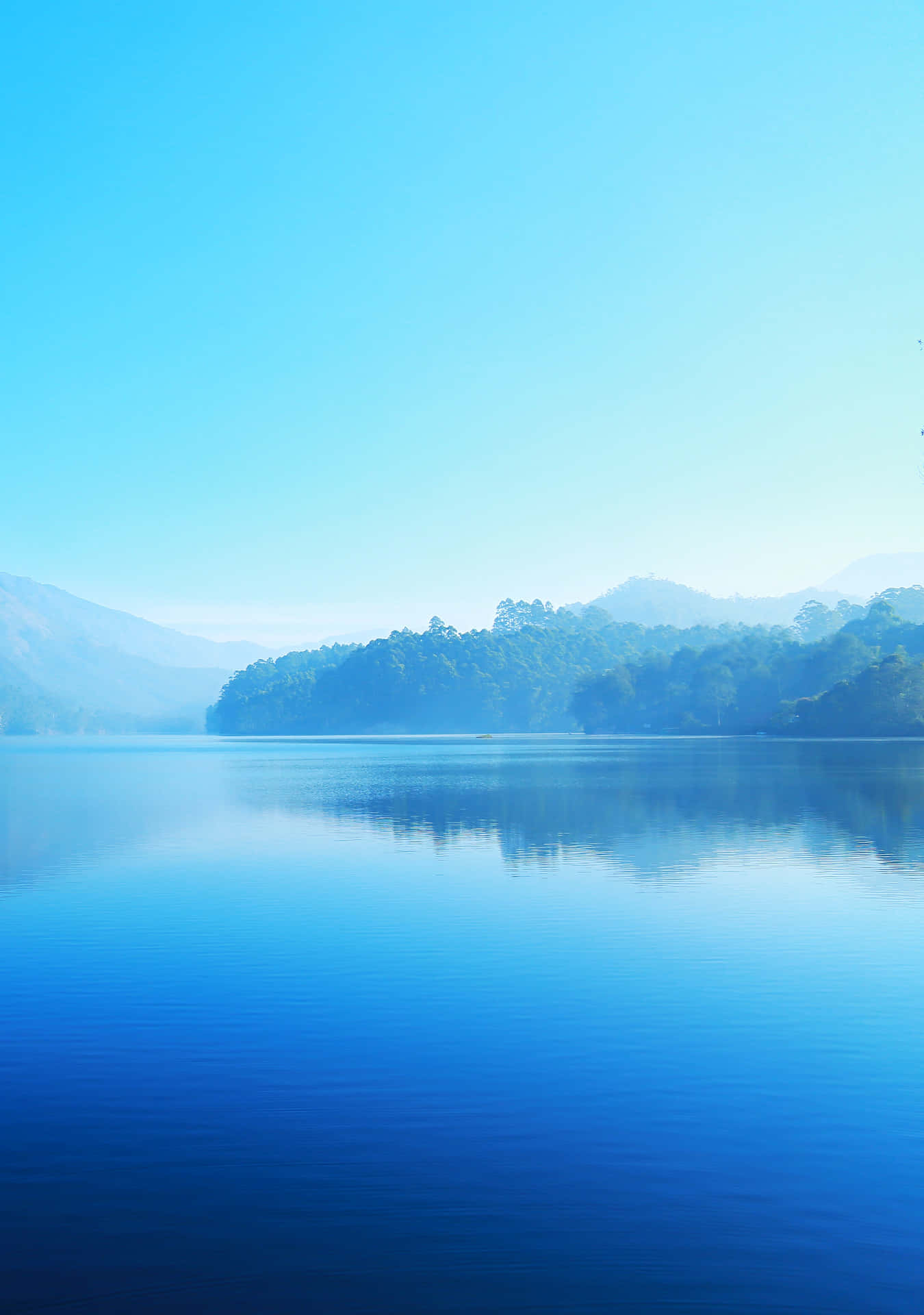 A Lake With Trees And Mountains In The Background