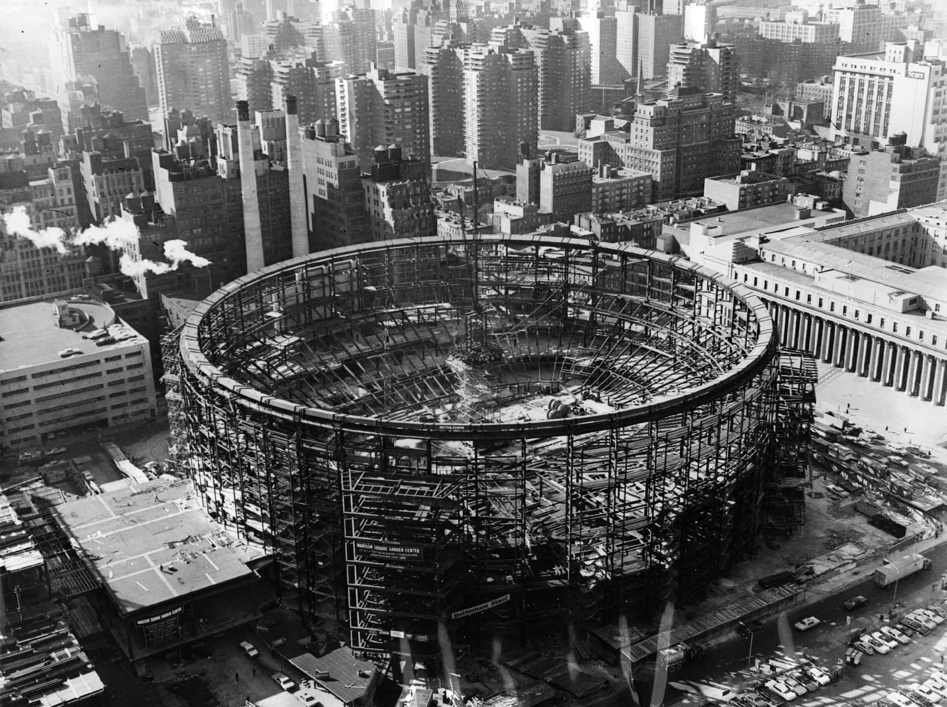 A Large Circular Building Under Construction In A City Background